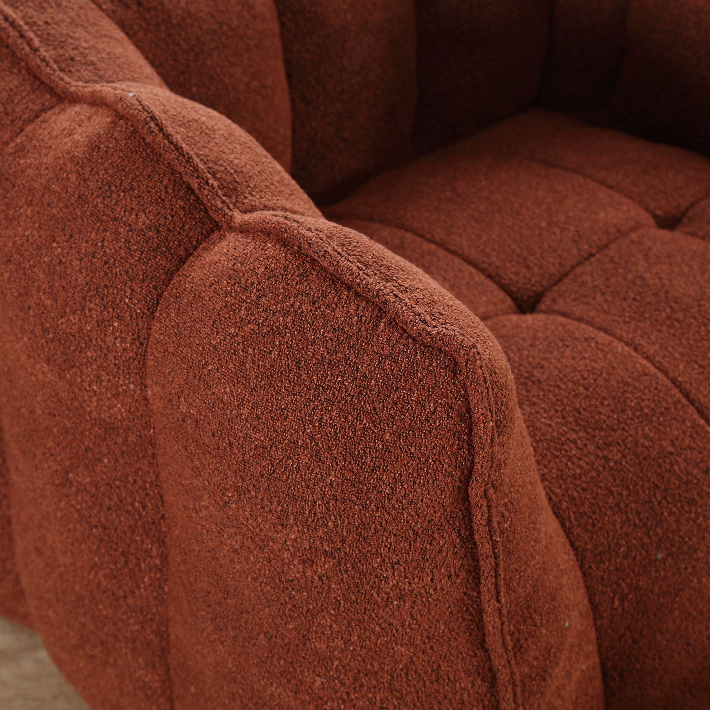 Textured rustcolored sofa armrest with tufted detail