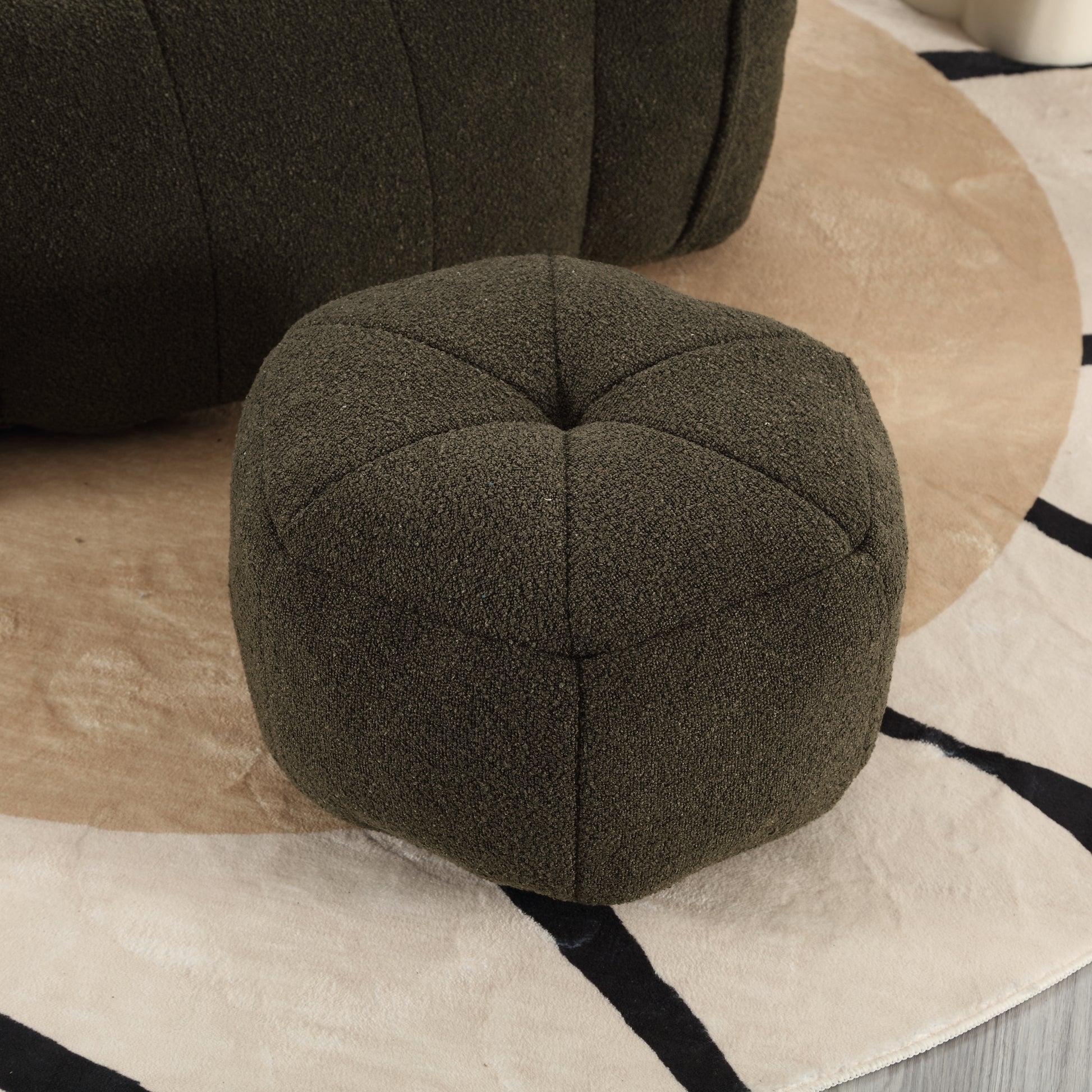 Dark green textured fabric pouf with tufted top on a patterned rug