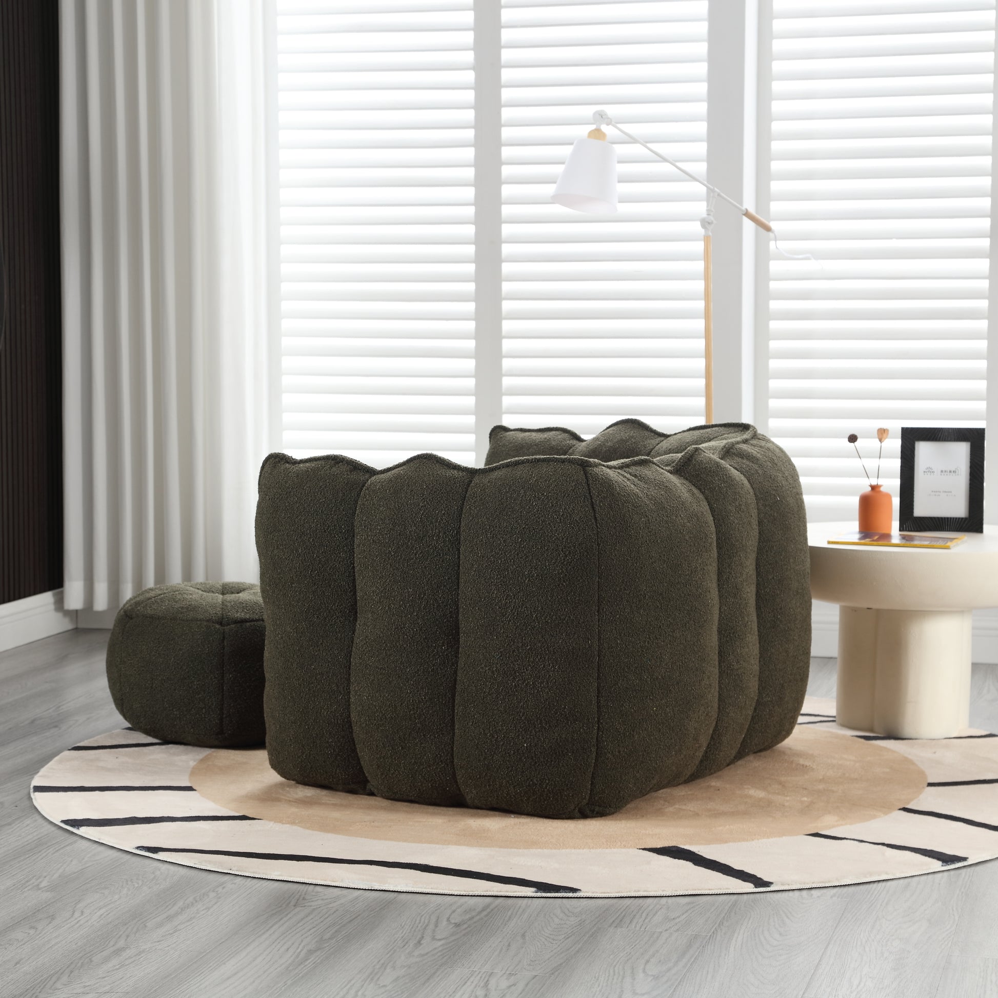 Dark green boucl accent chair with plush segmented design and matching ottoman