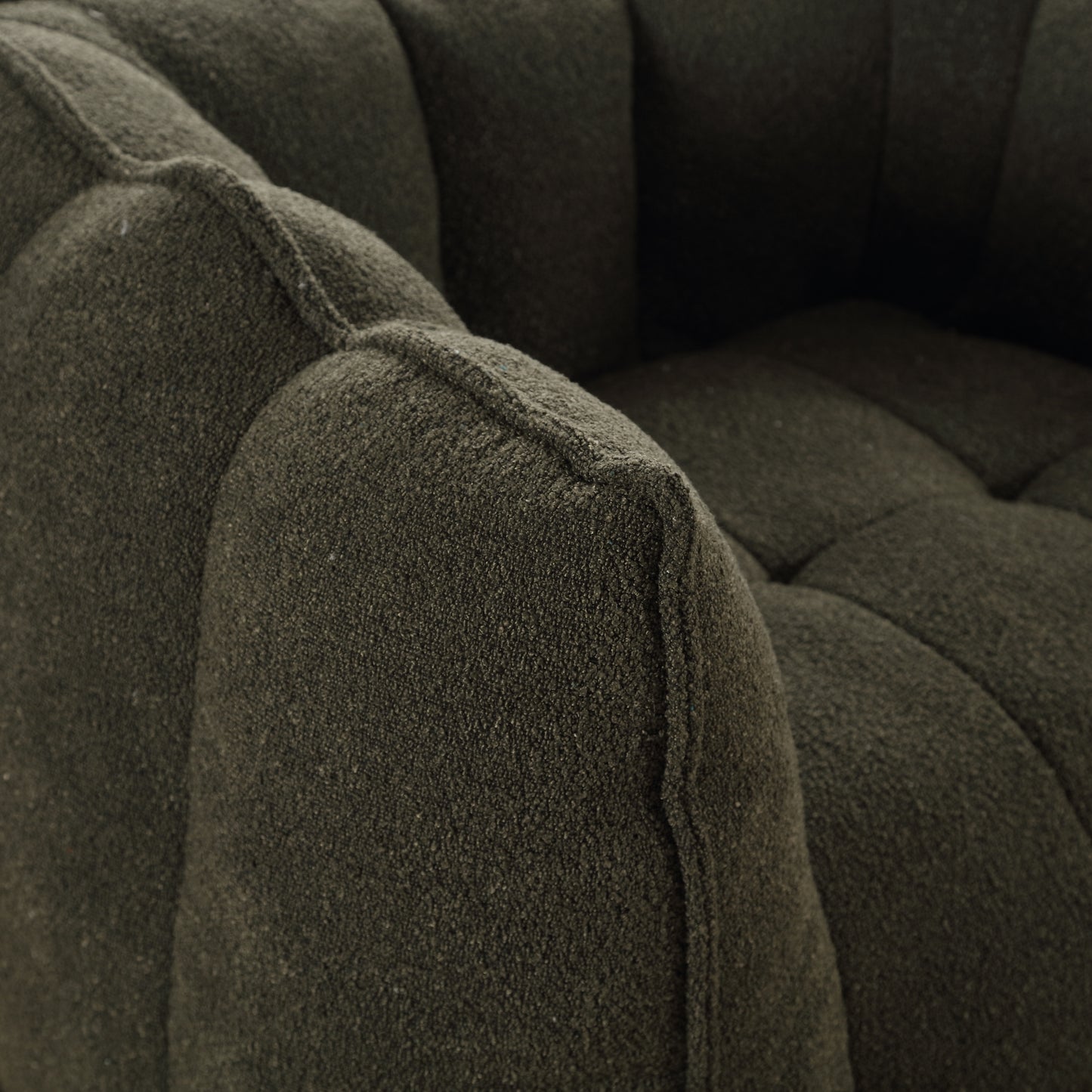 Closeup of a dark green textured boucle fabric on a modern armchair armrest