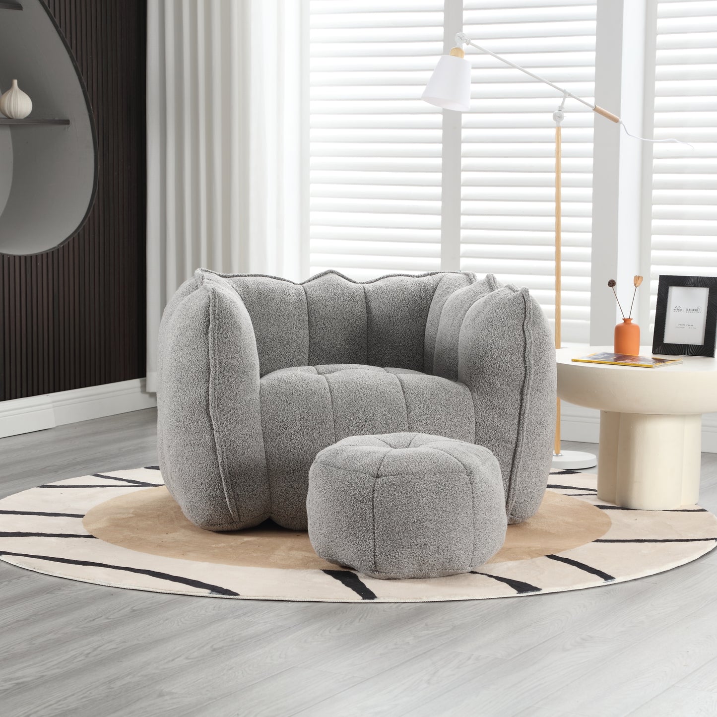 Plush grey armchair with scalloped back and matching ottoman perfect for modern living rooms