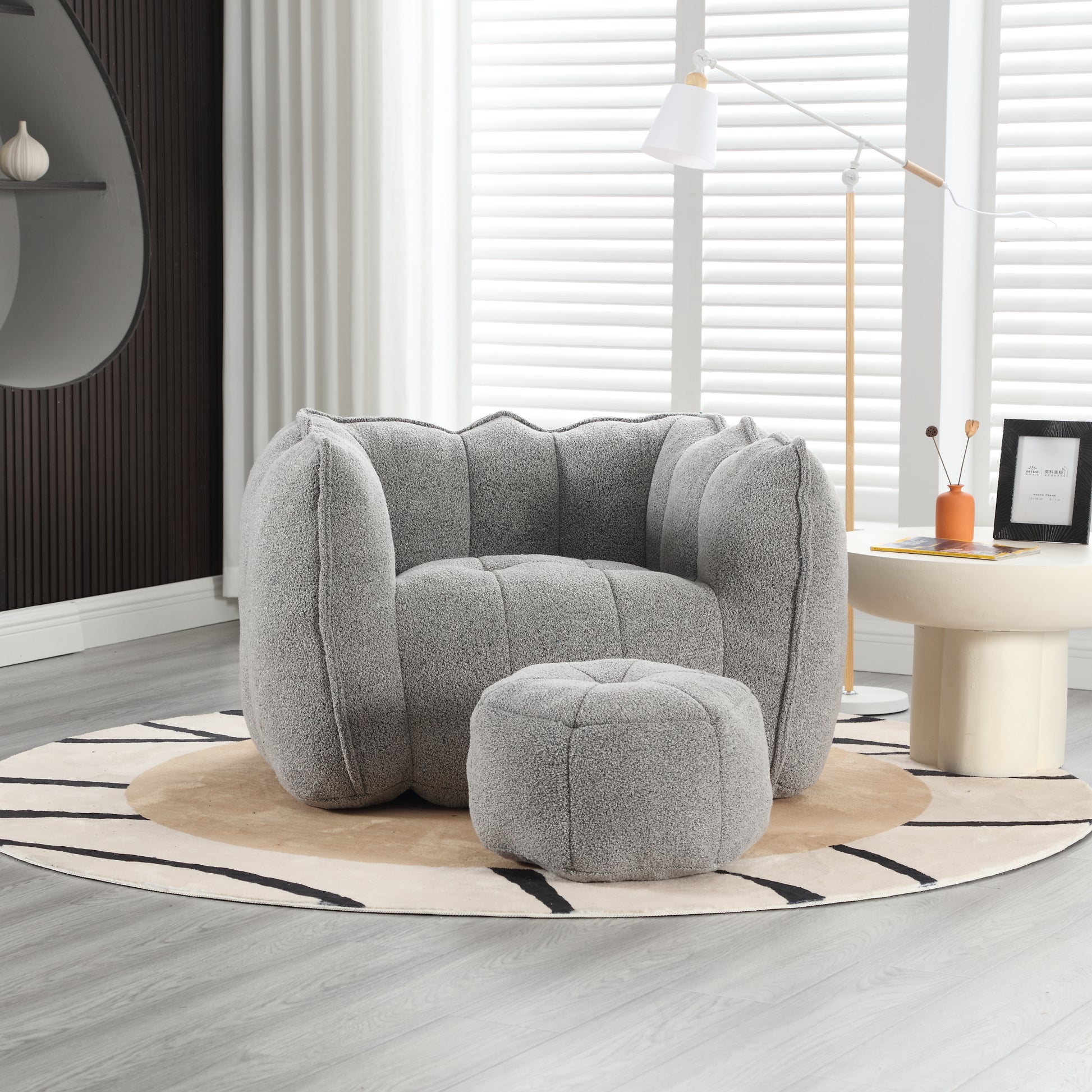Plush grey armchair with scalloped back and matching ottoman perfect for modern living rooms