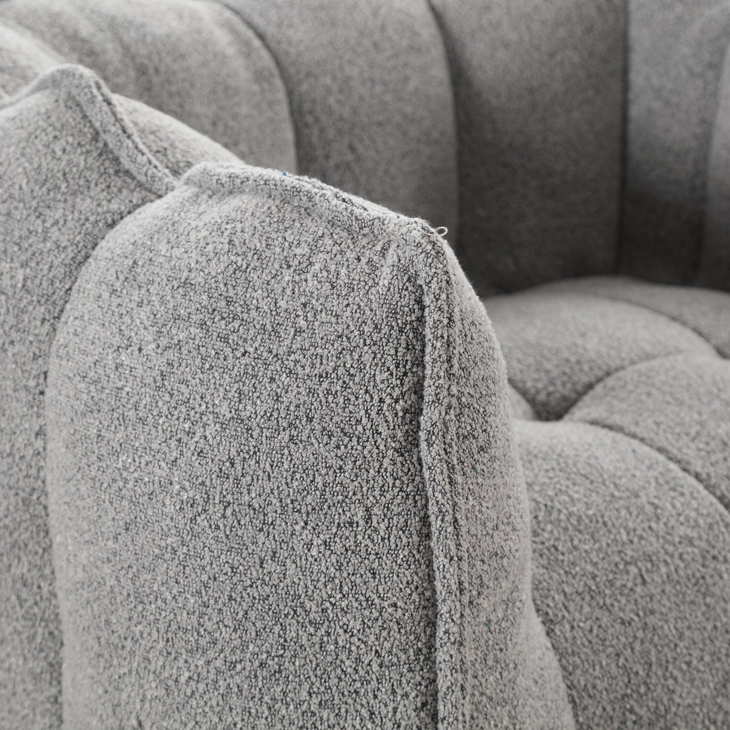 Closeup of a grey boucle armchair armrest with detailed textured fabric