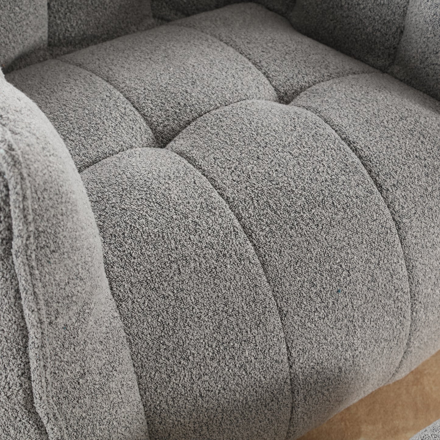 Closeup of textured grey boucle fabric on a tufted sofa cushion