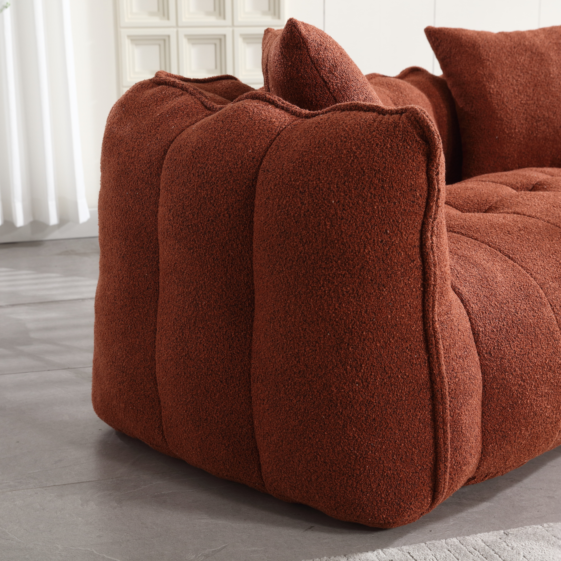 Plush terracotta boucl fabric sofa with tufted cushions and soft rounded armrest