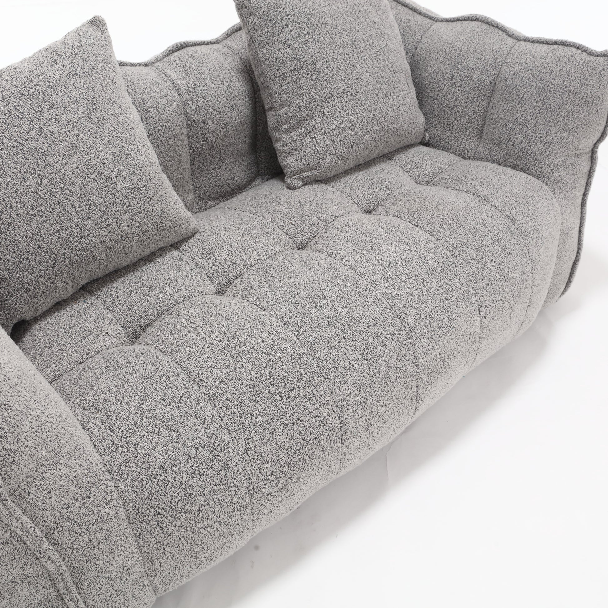 Gray boucle fabric sofa with tufted seat cushions and plush throw pillows