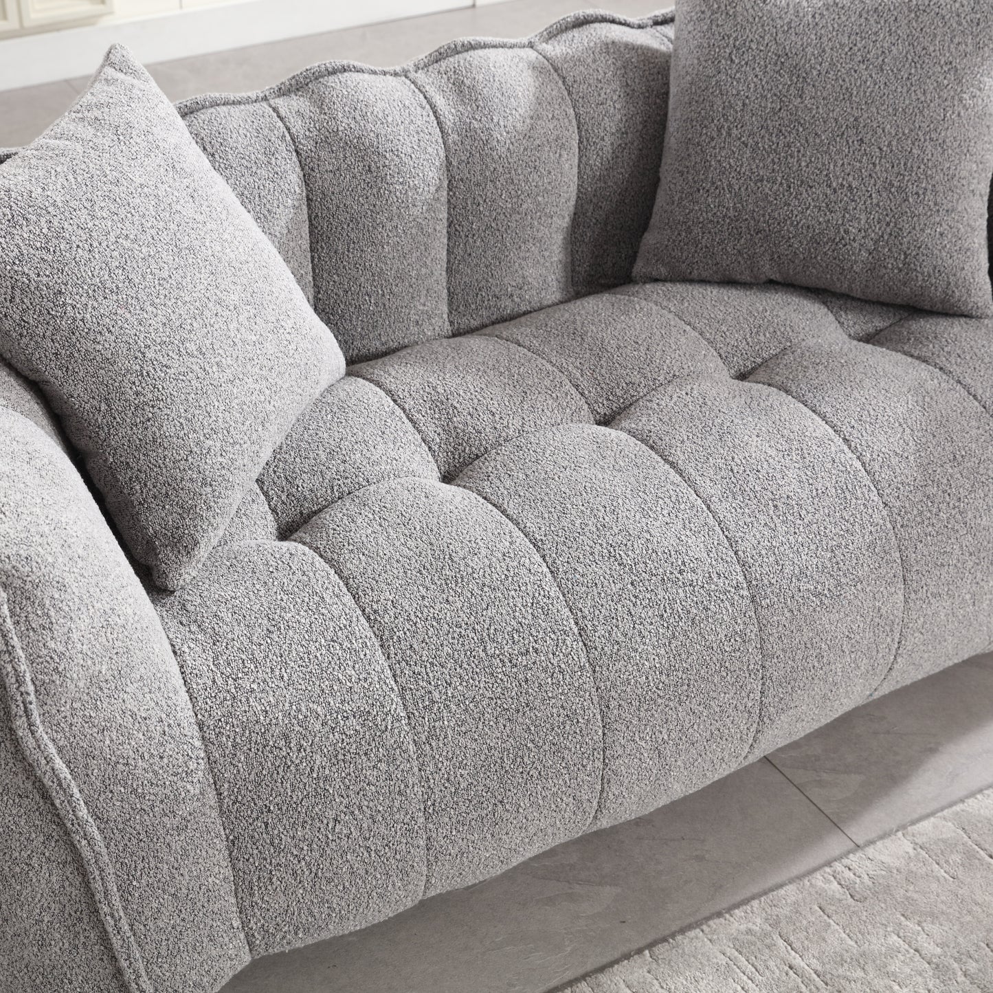 Tufted grey boucl sofa with plush throw pillows for a cozy living room