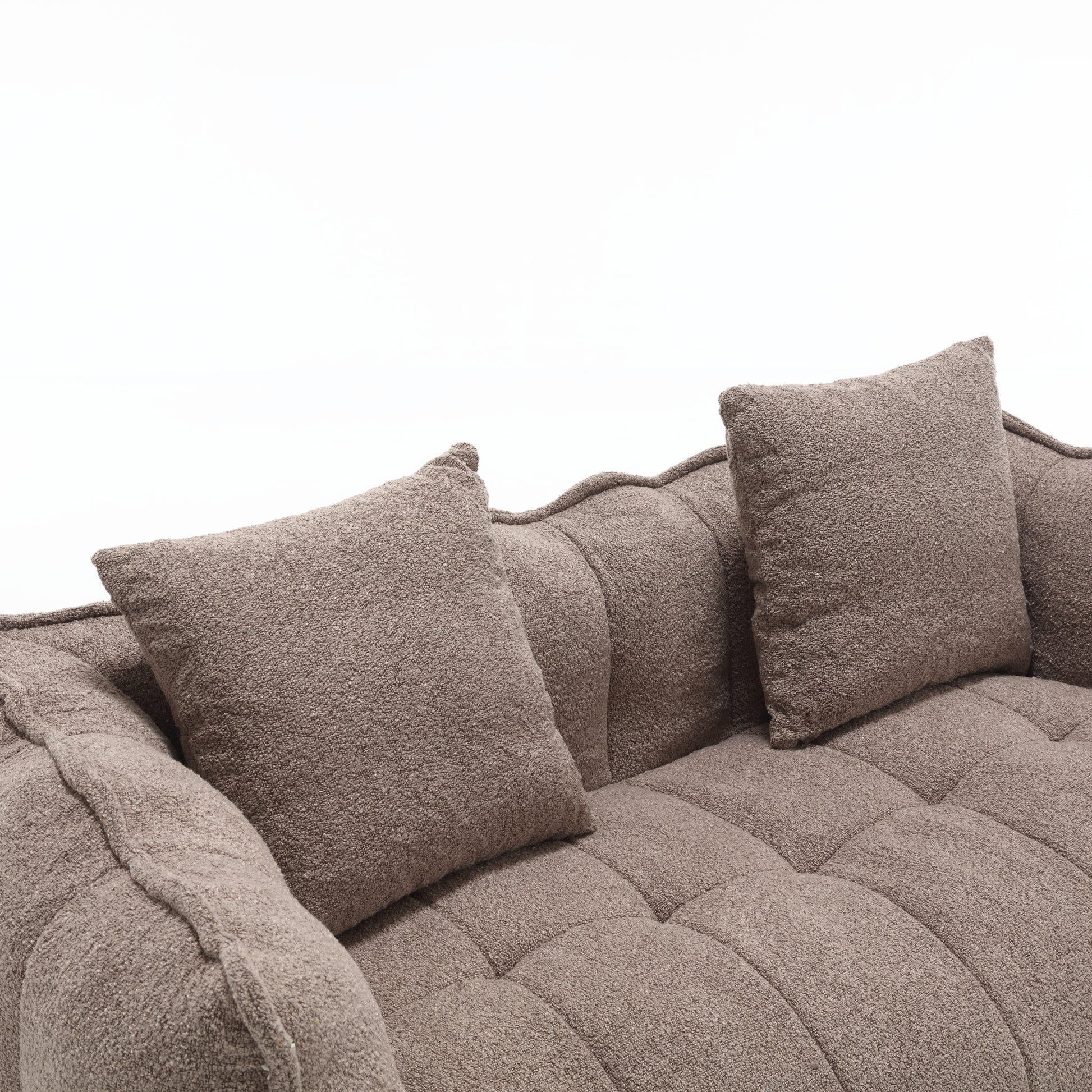 Plush taupe boucle fabric sofa with tufted seat cushions and textured throw pillows