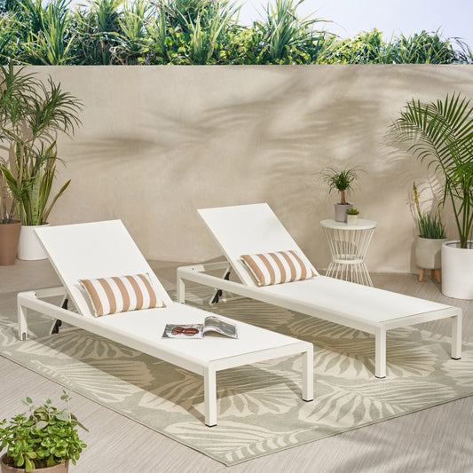 Two white aluminum lounge chairs with striped cushions on a patio rug outdoors