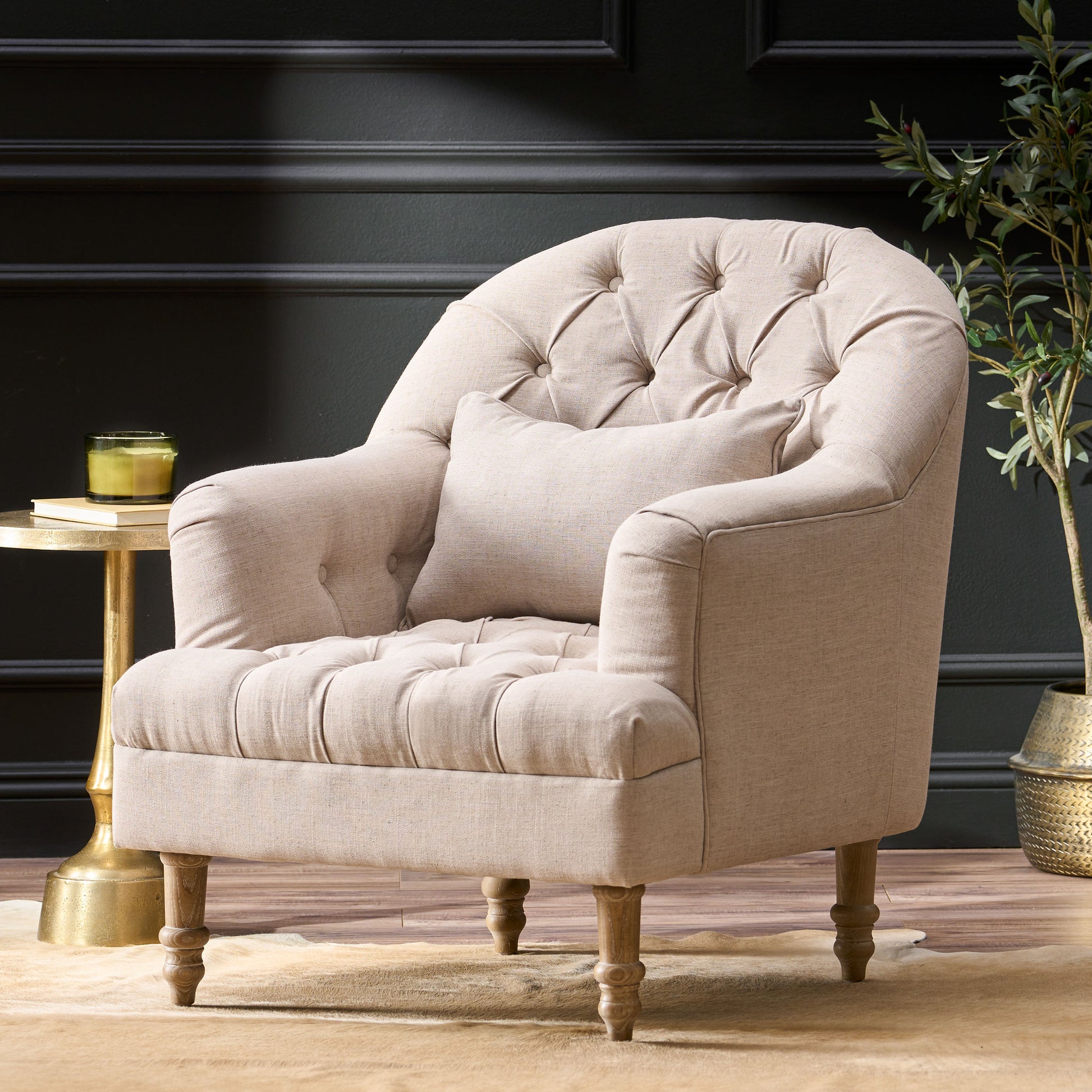 Tufted beige linen armchair with rolled arms and a single lumbar pillow for a cozy living room
