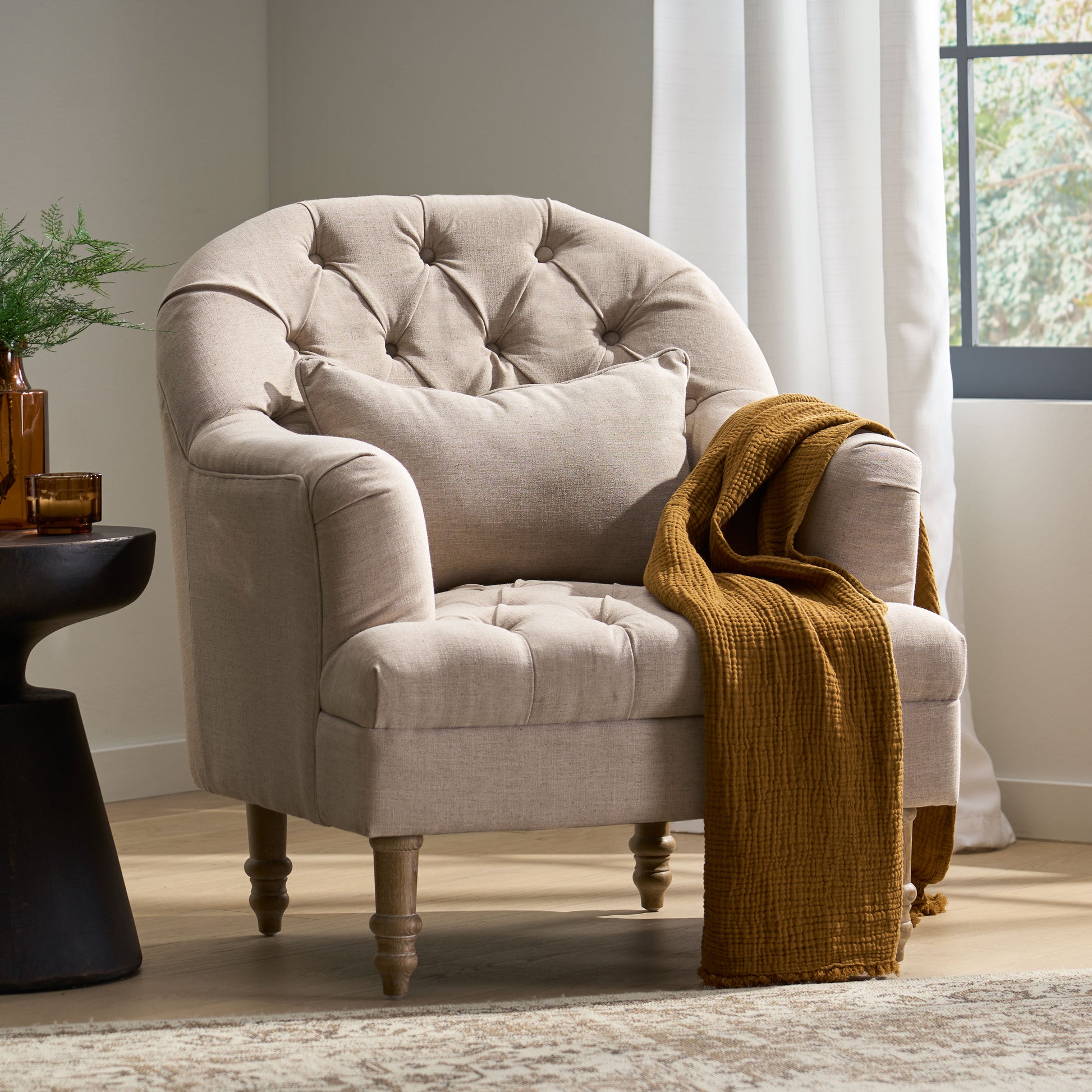 Tufted linen accent chair in light beige with rolled arms and a throw pillow