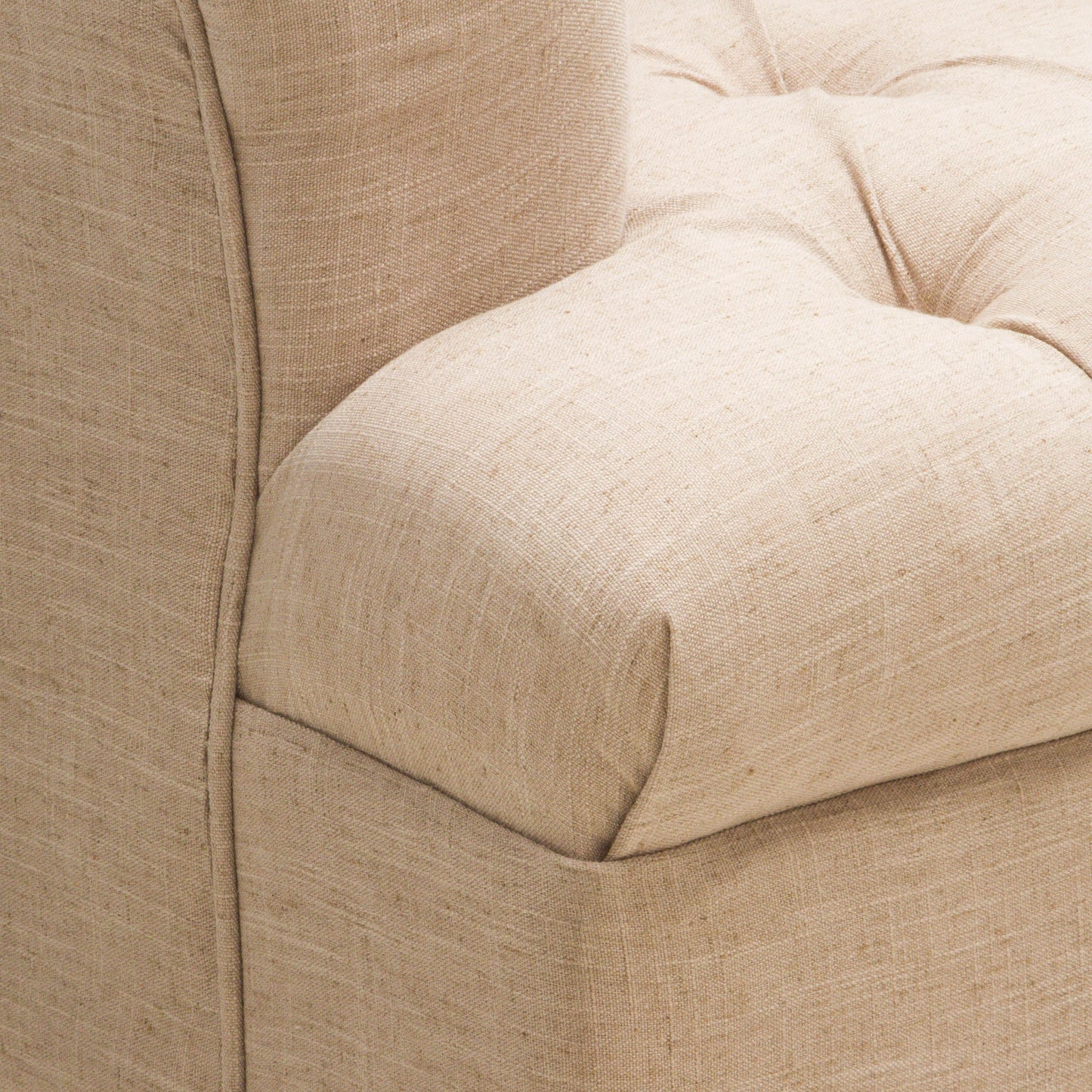 Closeup of a tufted beige linen armchair armrest with subtle texture variations