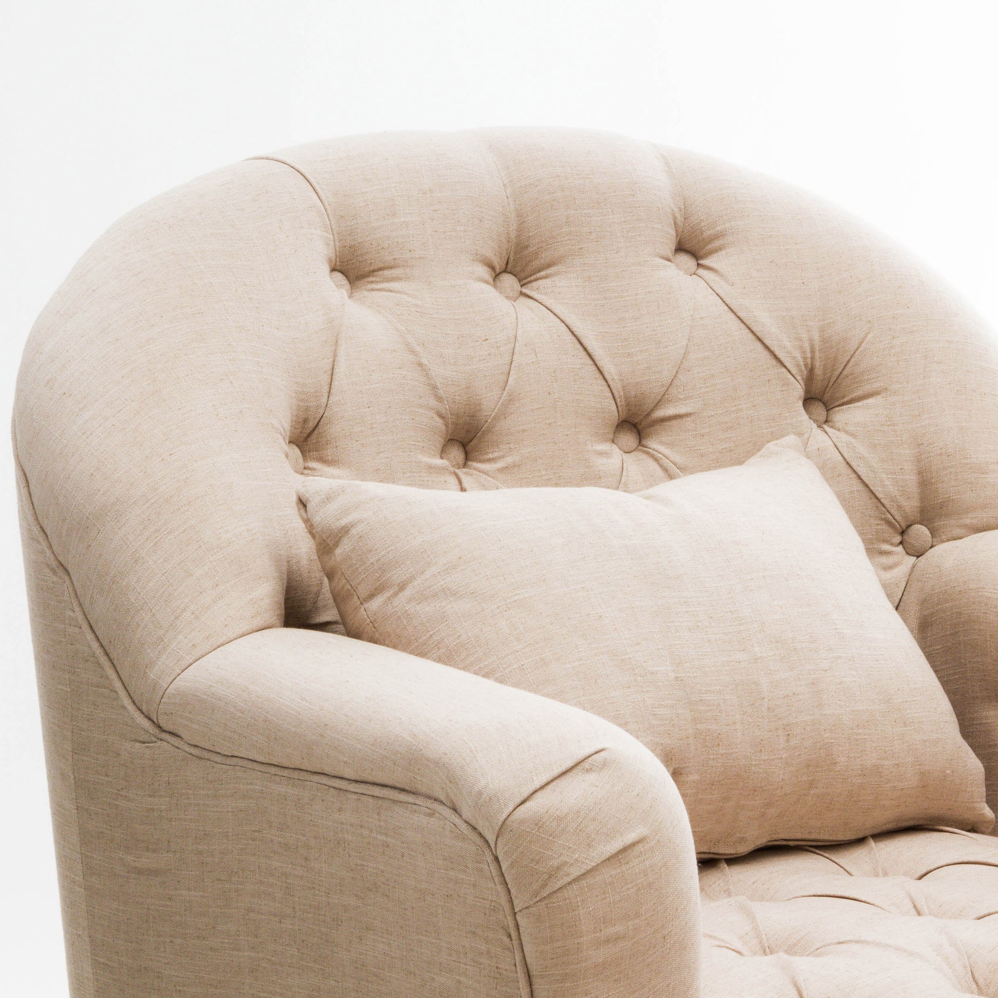 Tufted beige armchair with a matching accent pillow perfect for living room comfort