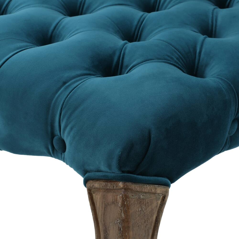 Teal velvet ottoman with deep button tufting and carved wooden legs