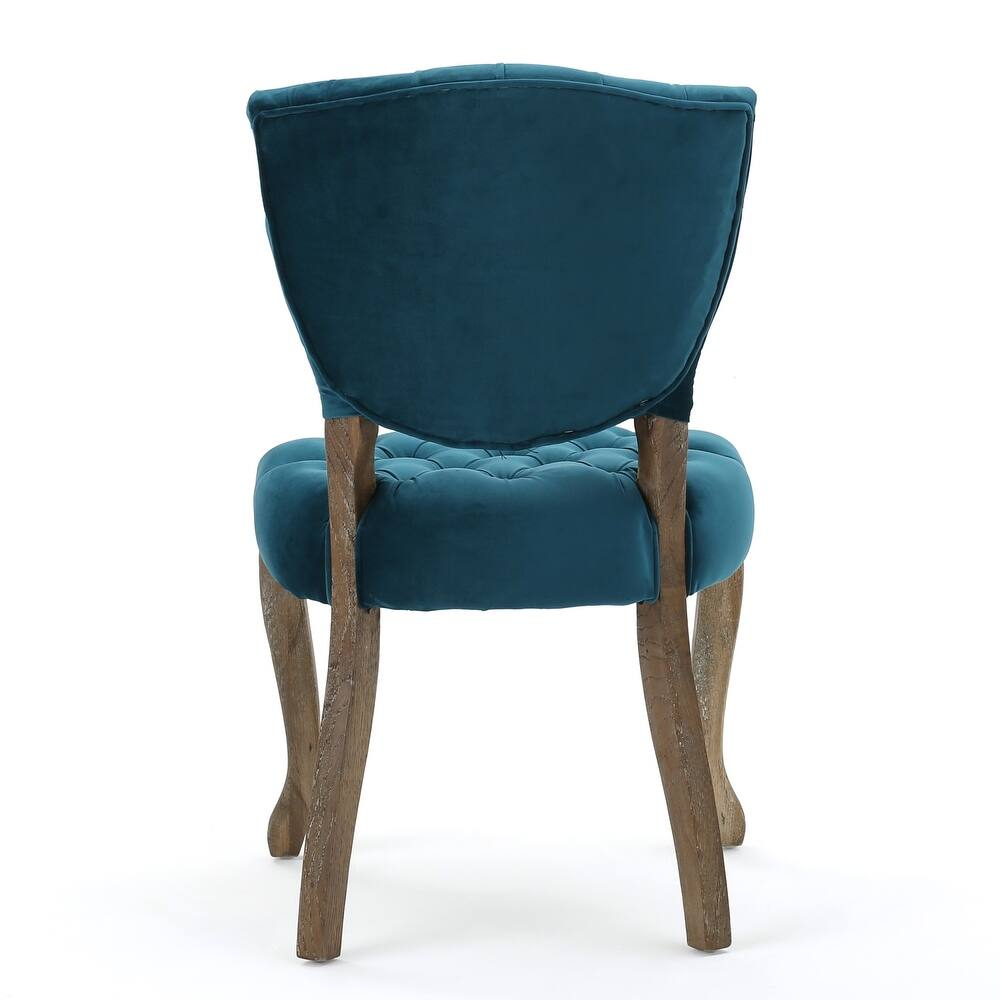 Deep teal velvet dining chair with tufted seat and distressed wood legs
