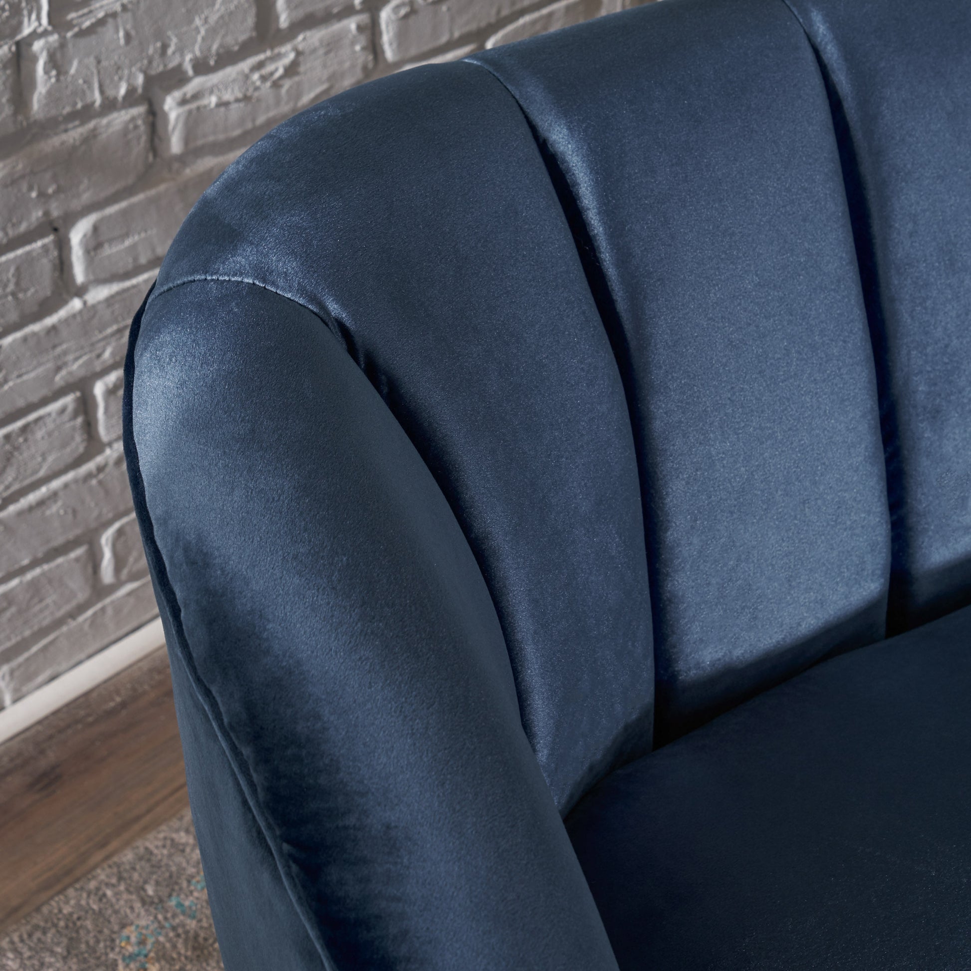 Closeup of navy velvet armchair with channel tufting on the backrest and armrest