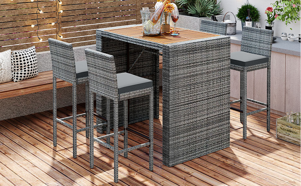 Gray rattan bar set with four stools and a table on a wooden deck