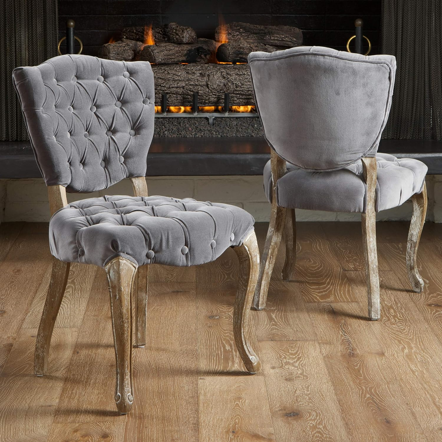 Grey velvet dining chair with button tufting and distressed wood legs