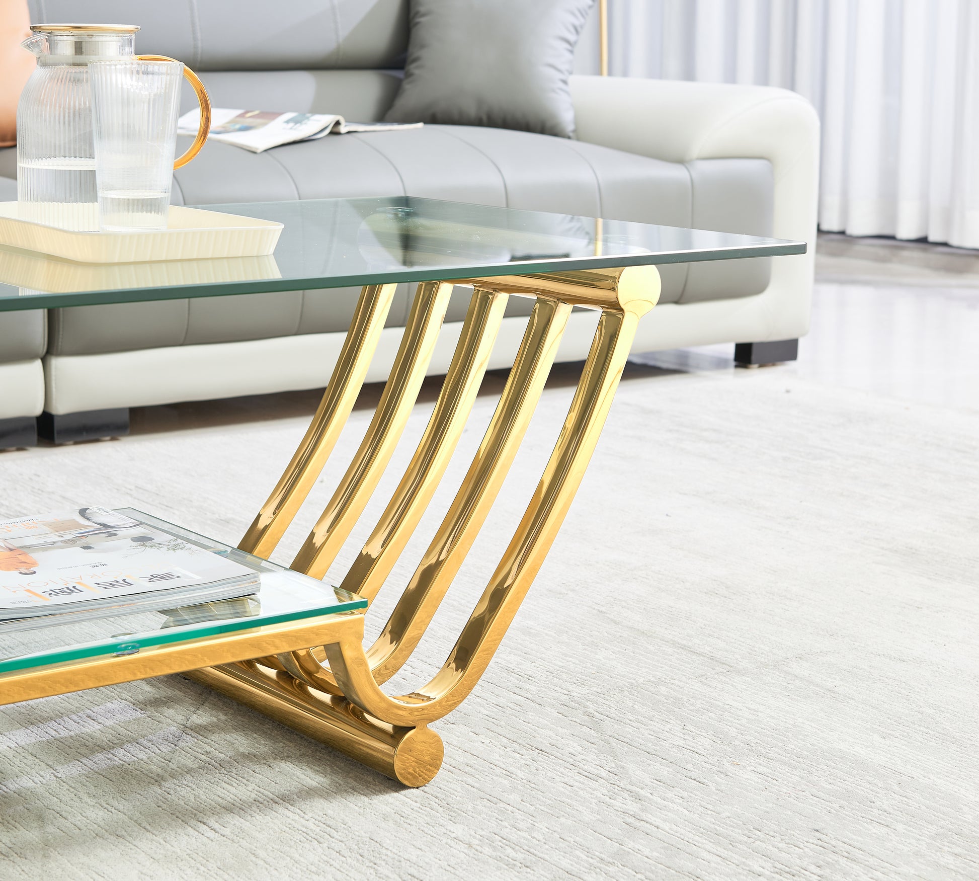 Modern glass coffee table with polished gold metal base and curved legs