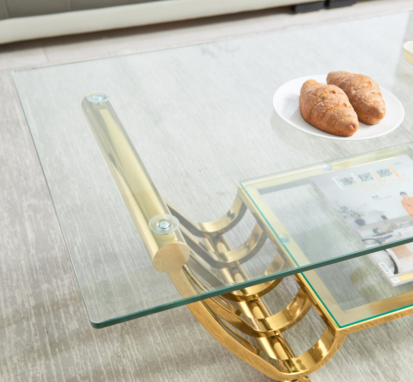 Modern gold and glass coffee table with curved base and magazine on top
