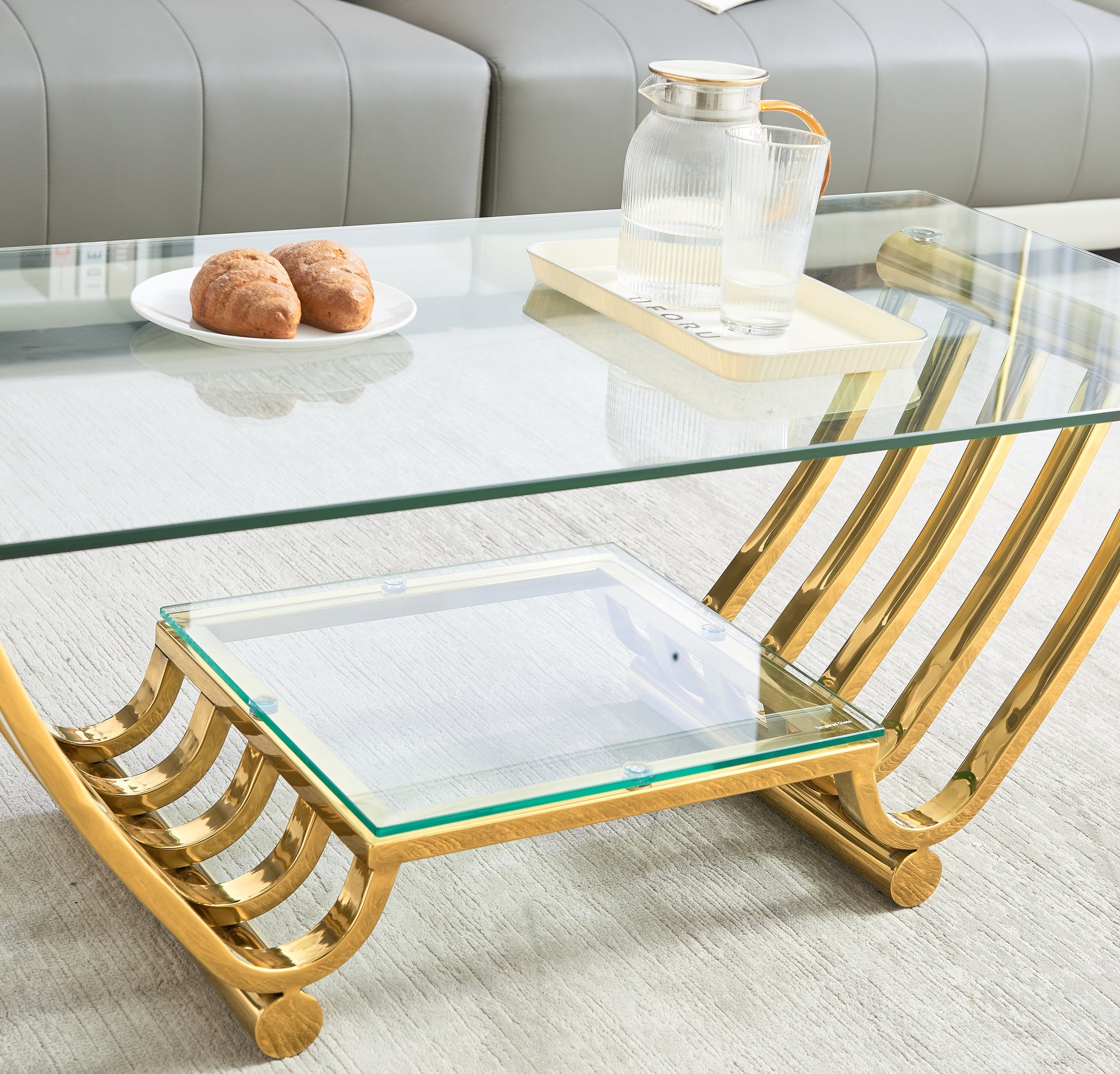 Modern glass coffee table with gold metal frame and ornate curved legs