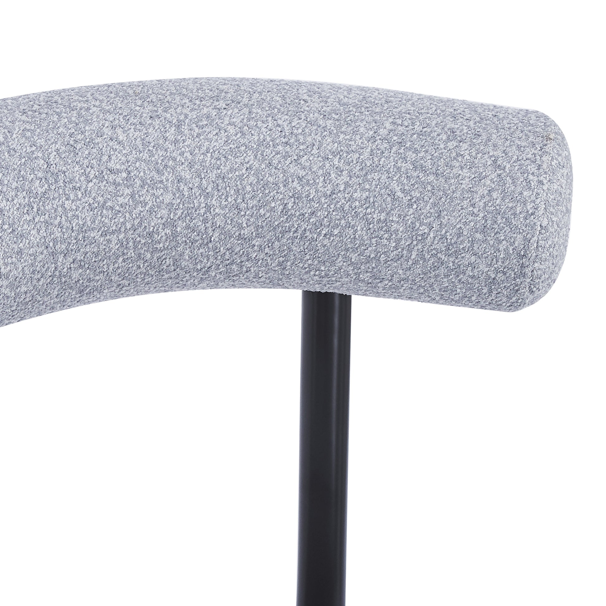 Closeup of a curved light grey upholstered chair back with a textured fabric on a black metal leg