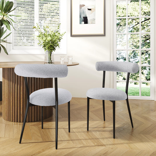 Two light grey boucle fabric chairs with black metal legs and round seats in a dining room