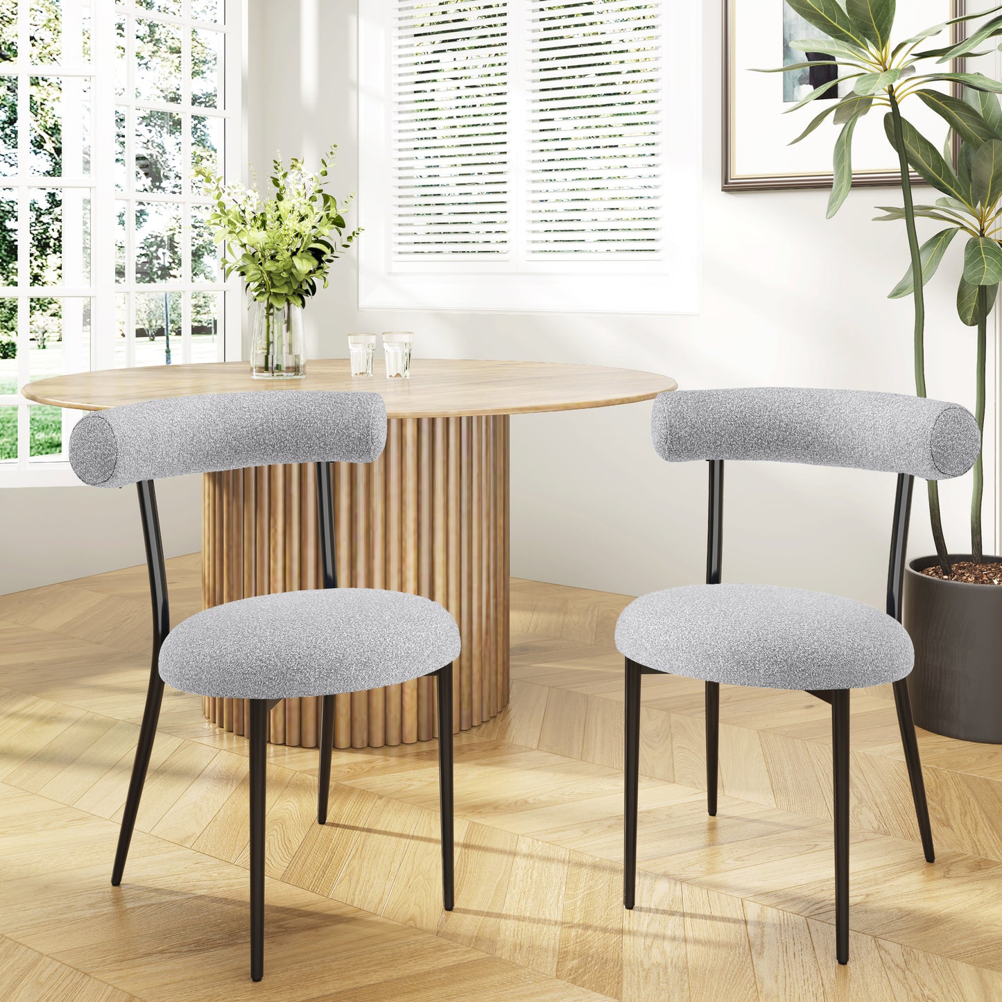 Two light grey fabric dining chairs with curved backrests and black metal legs