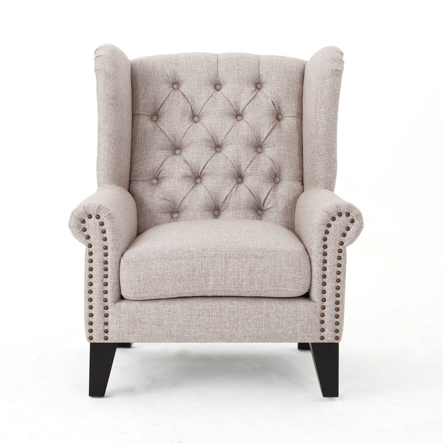 Tufted beige fabric wingback chair with brass nailhead trim accents and dark wood legs