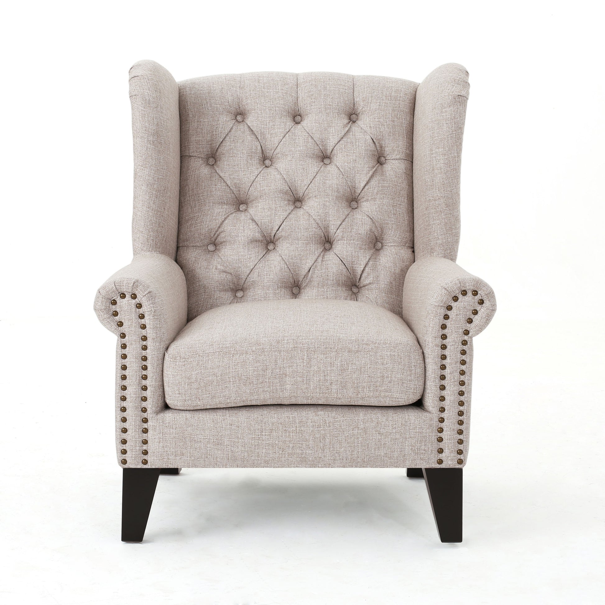 Tufted beige fabric wingback chair with brass nailhead trim accents and dark wood legs