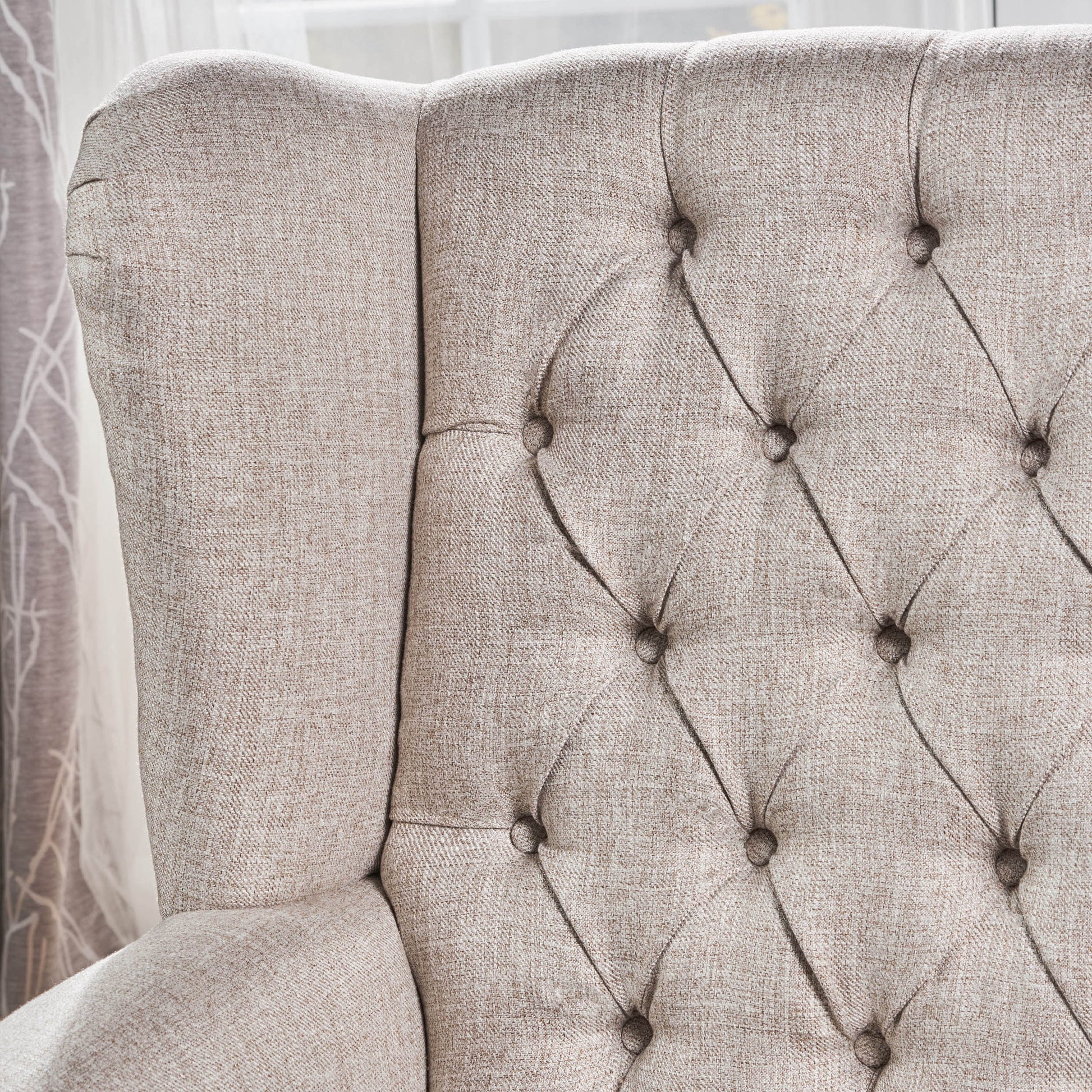 Tufted beige linen upholstered wingback armchair side profile with diamond stitching detail