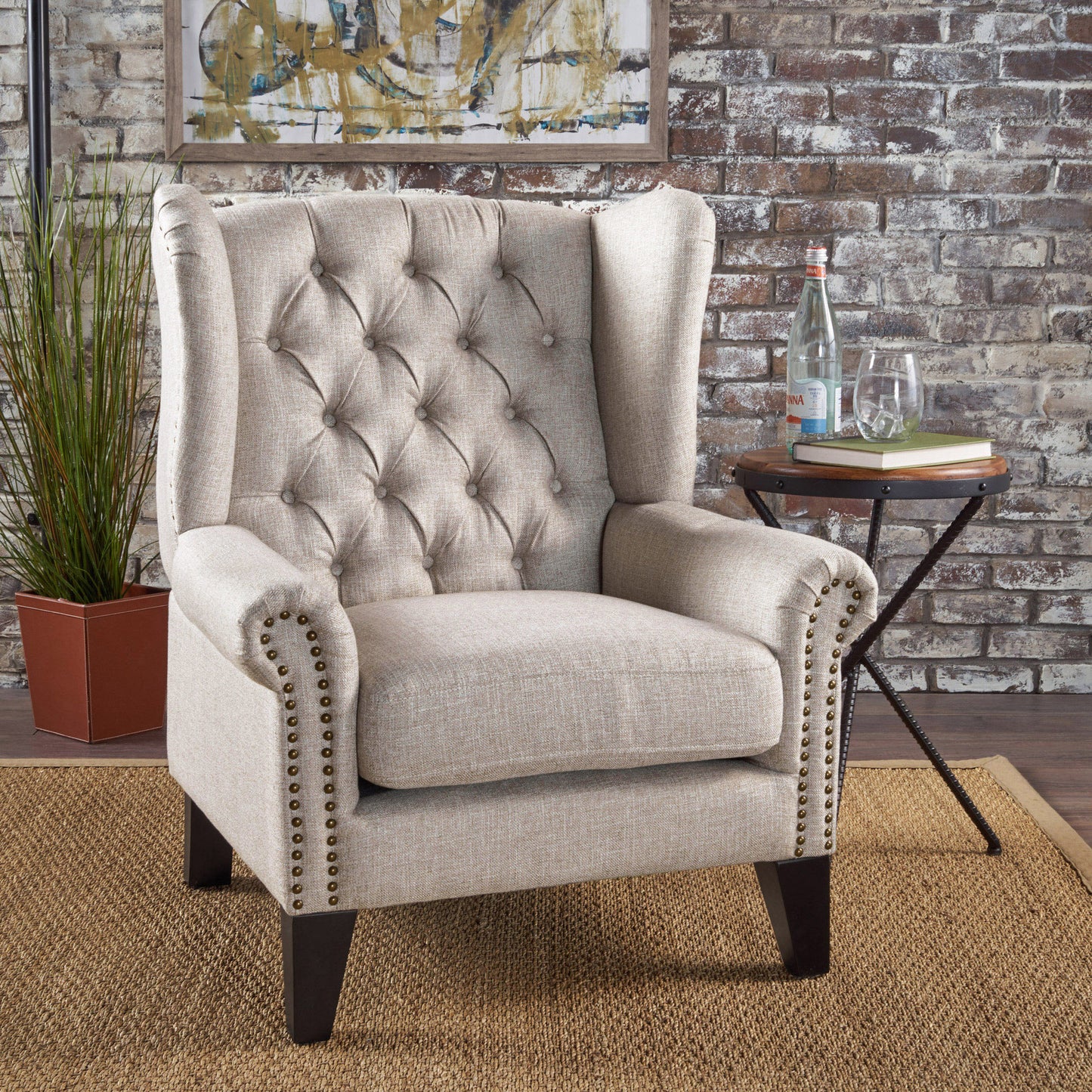 Tufted linen wingback armchair in light beige with nailhead trim and dark wooden legs