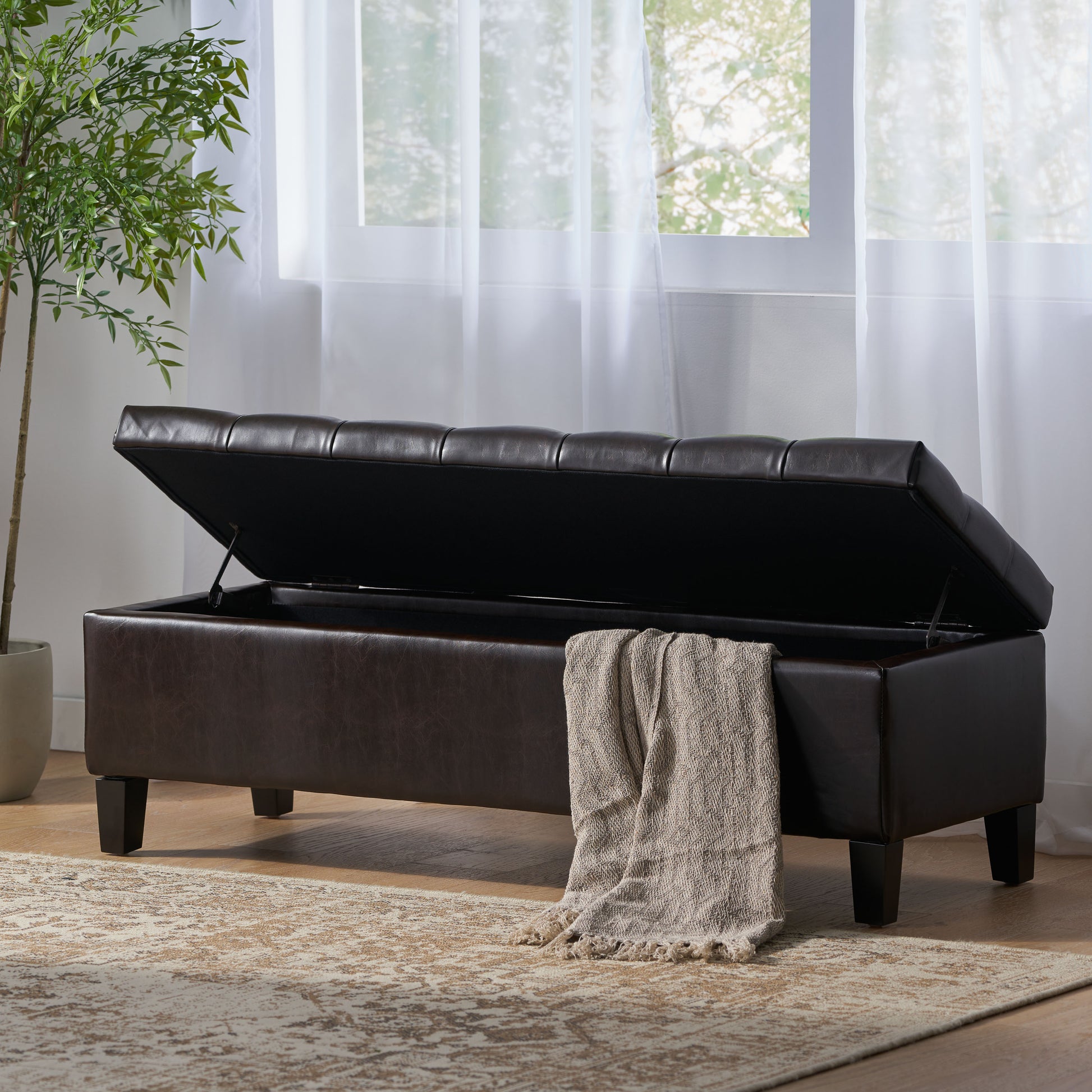 Tufted dark brown faux leather storage ottoman with lid open showing spacious interior