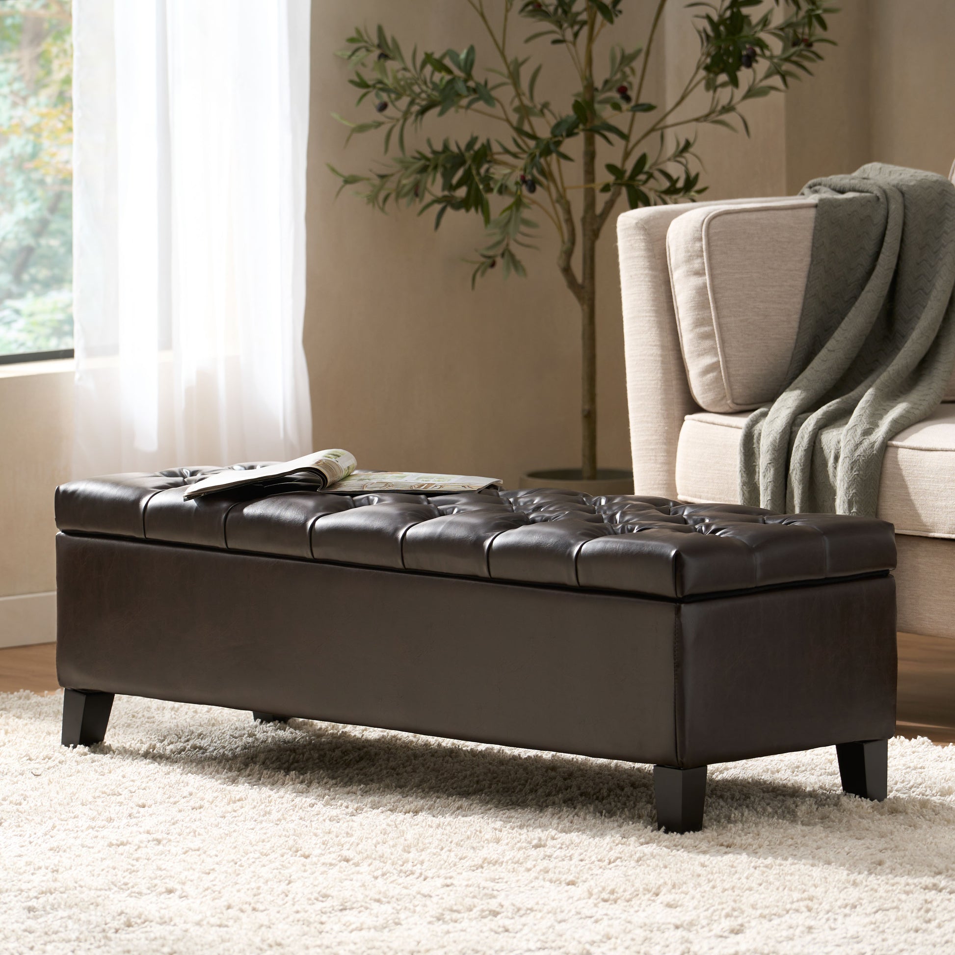 Dark brown faux leather storage ottoman with tufted top and wooden legs