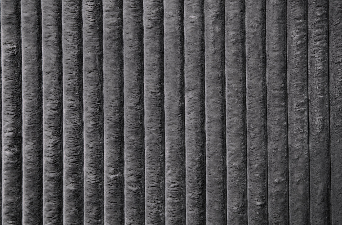 Closeup of textured dark grey corduroy fabric with distinct vertical ridges