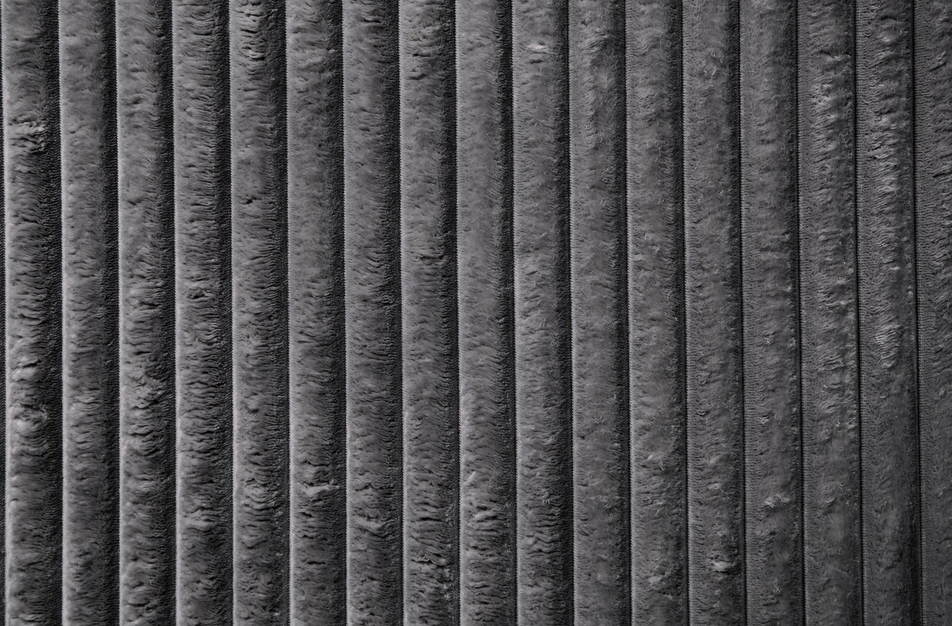 Closeup of textured dark grey corduroy fabric with distinct vertical ridges