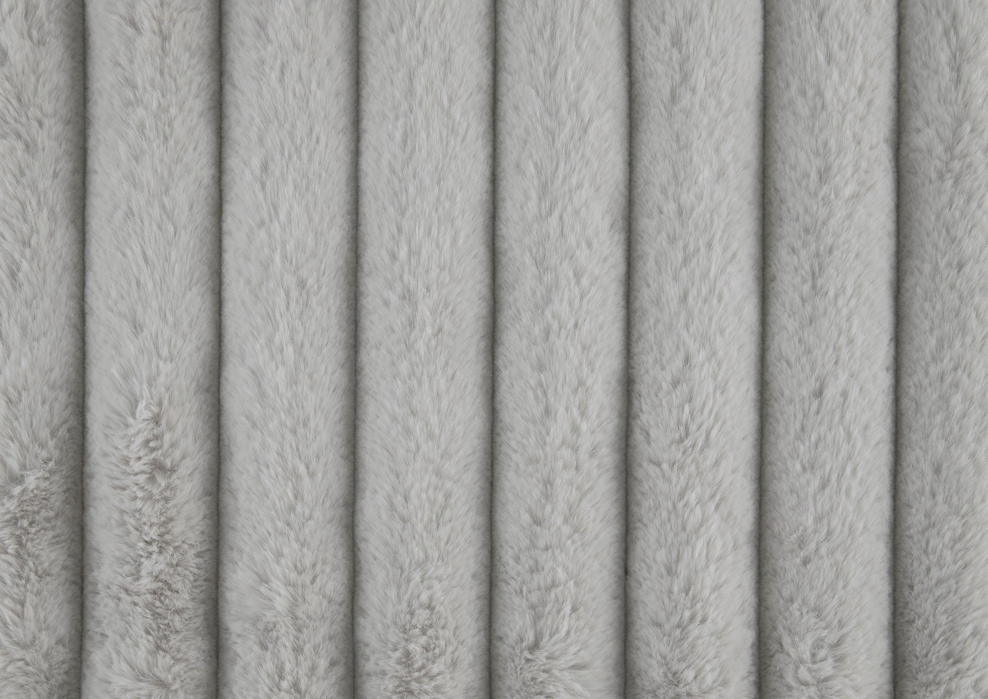 Closeup of soft light gray faux fur fabric with vertical channel quilting