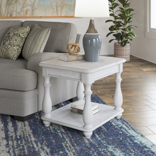 White distressed end table with carved legs and two shelves next to a sofa