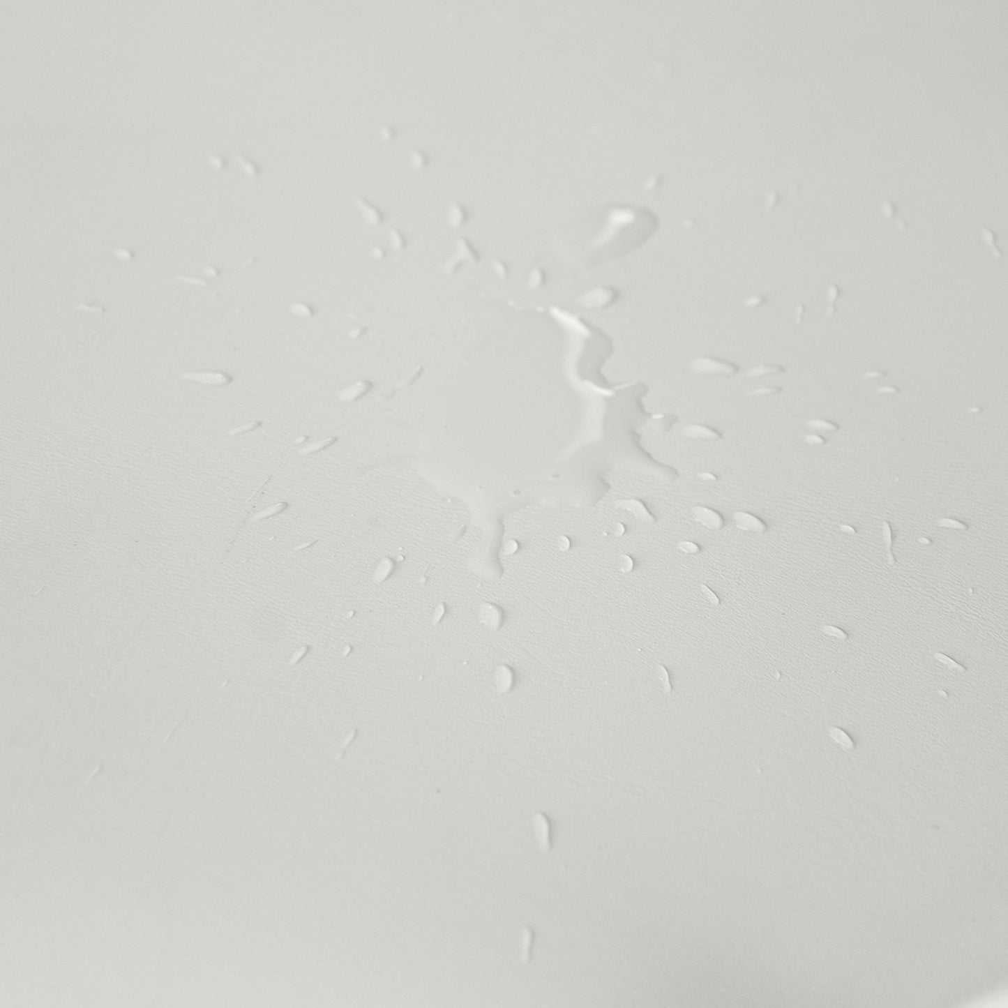 Water droplets on a light gray textured surface showcasing waterrepellent fabric
