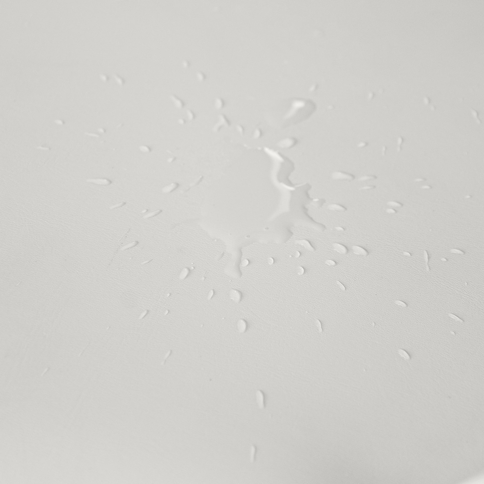 Water droplets on a light gray textured surface showcasing waterrepellent fabric