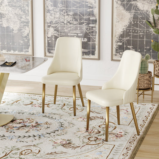 Two cream velvet dining chairs with gold legs arranged around a marble table