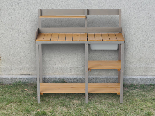 Gray wooden potting bench with two shelves and a sink for gardening projects