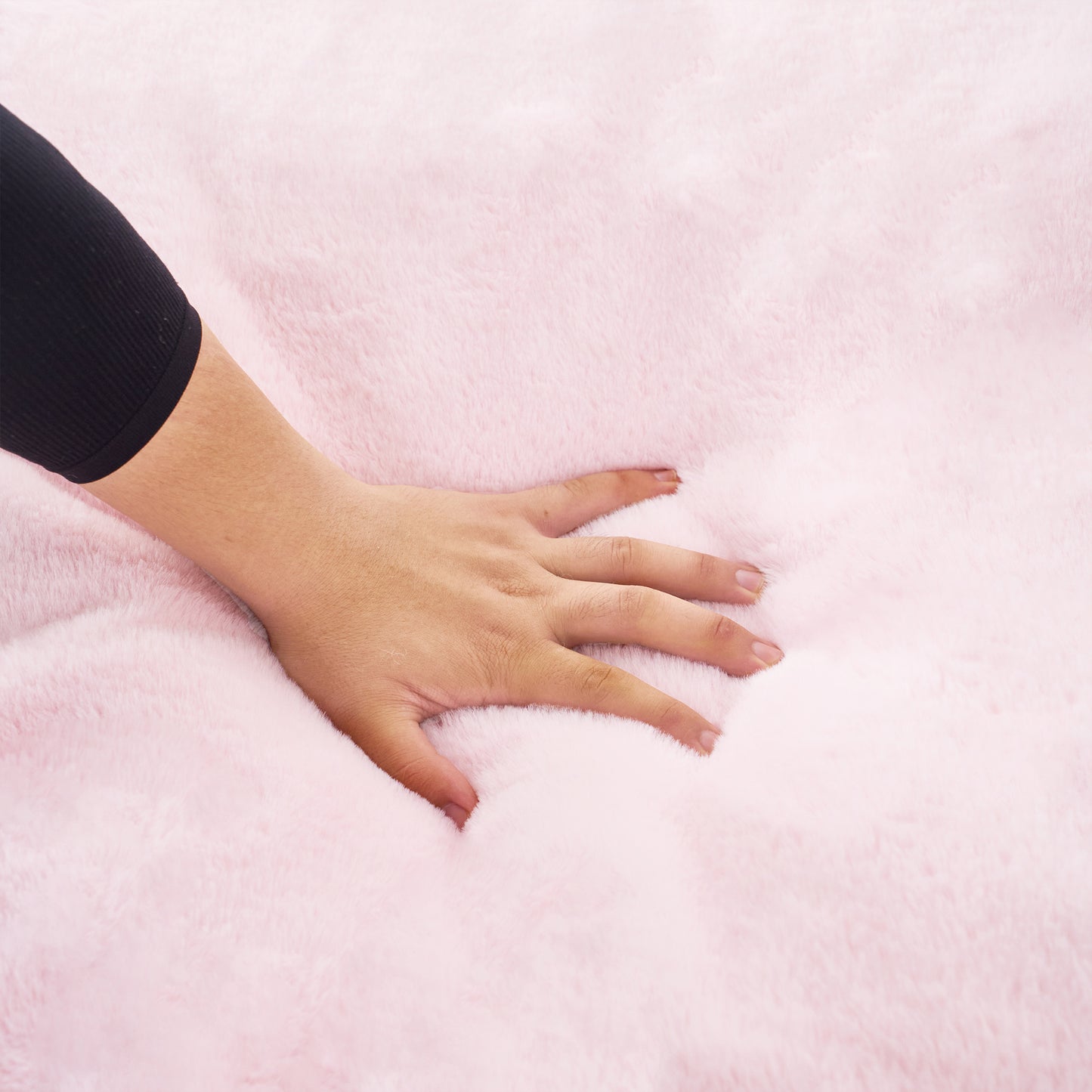 Closeup of hand pressing into soft pink plush fabric showing depth and comfort