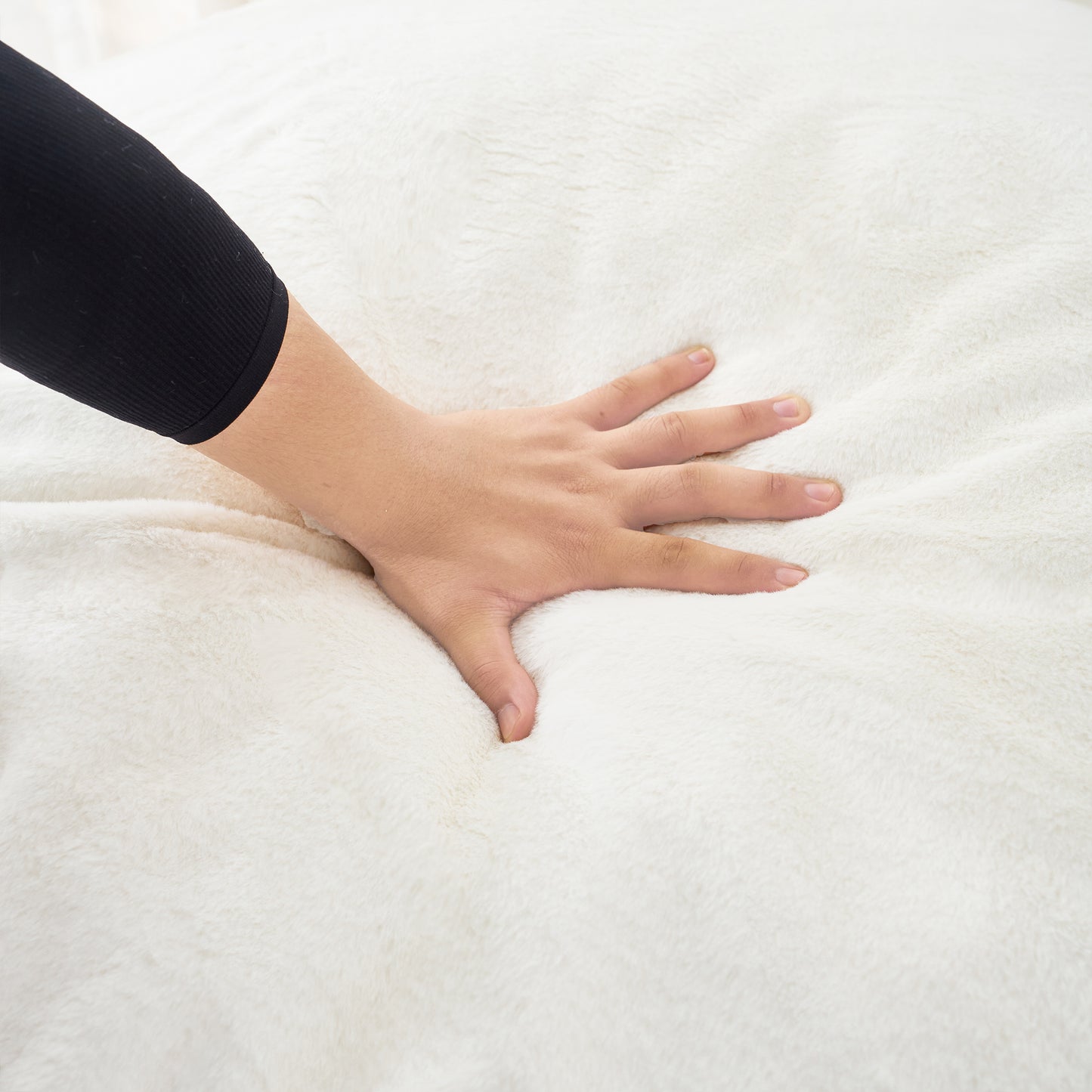 Hand pressing into soft cream fuzzy blanket highlighting plush texture for cozy comfort