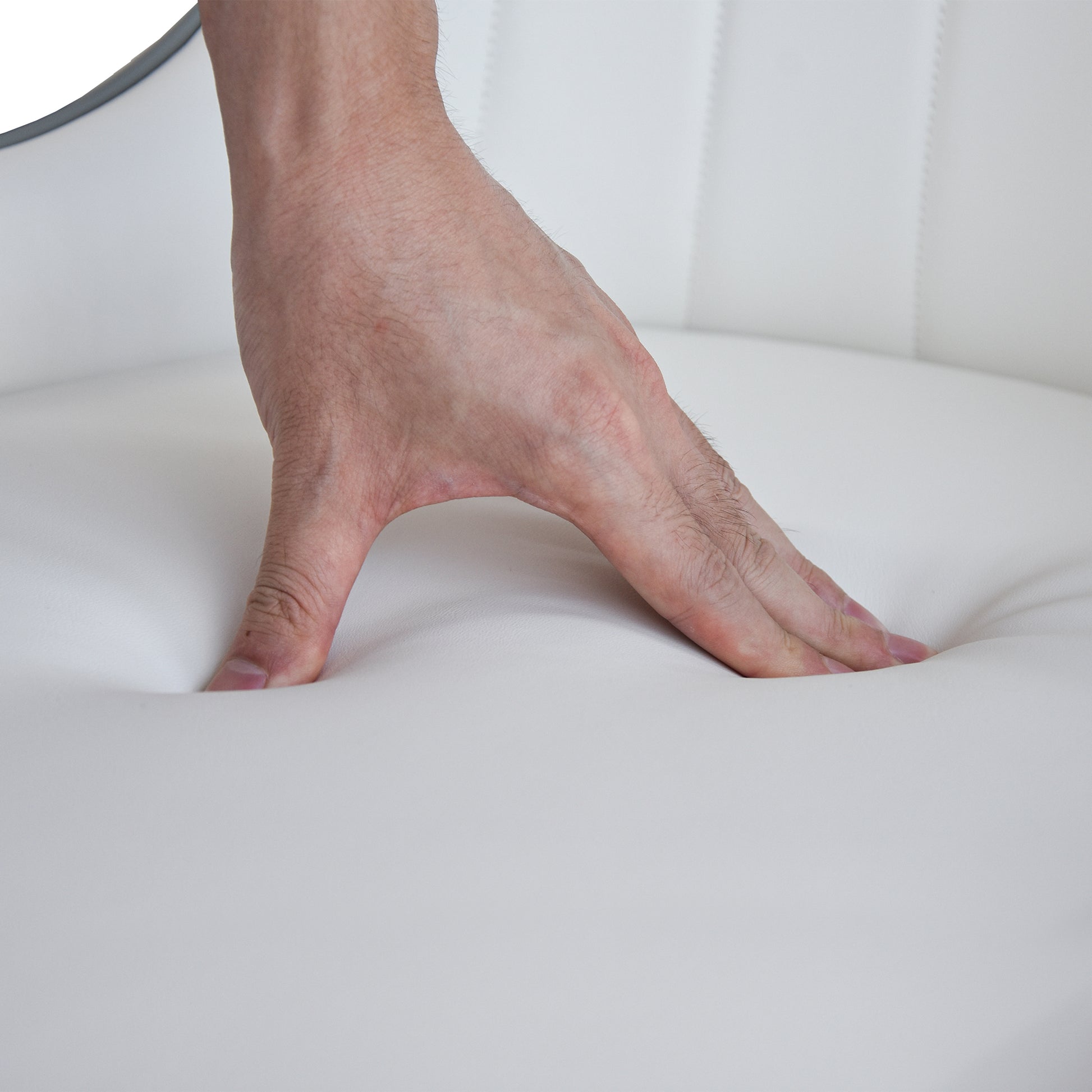 Hand pressing into soft white faux leather chair cushion highlighting comfort