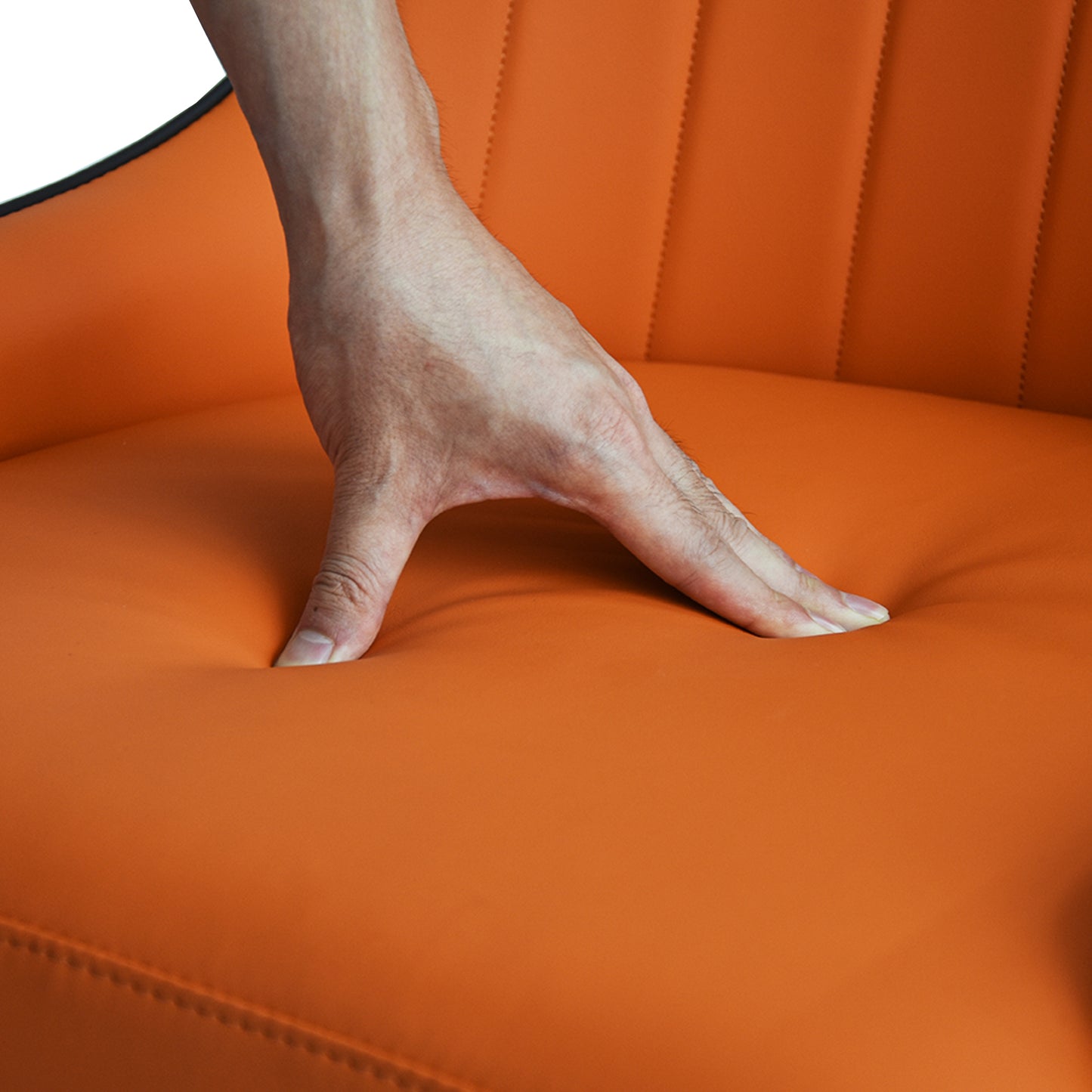Hand pressing into plush orange vegan leather seat cushion for comfort