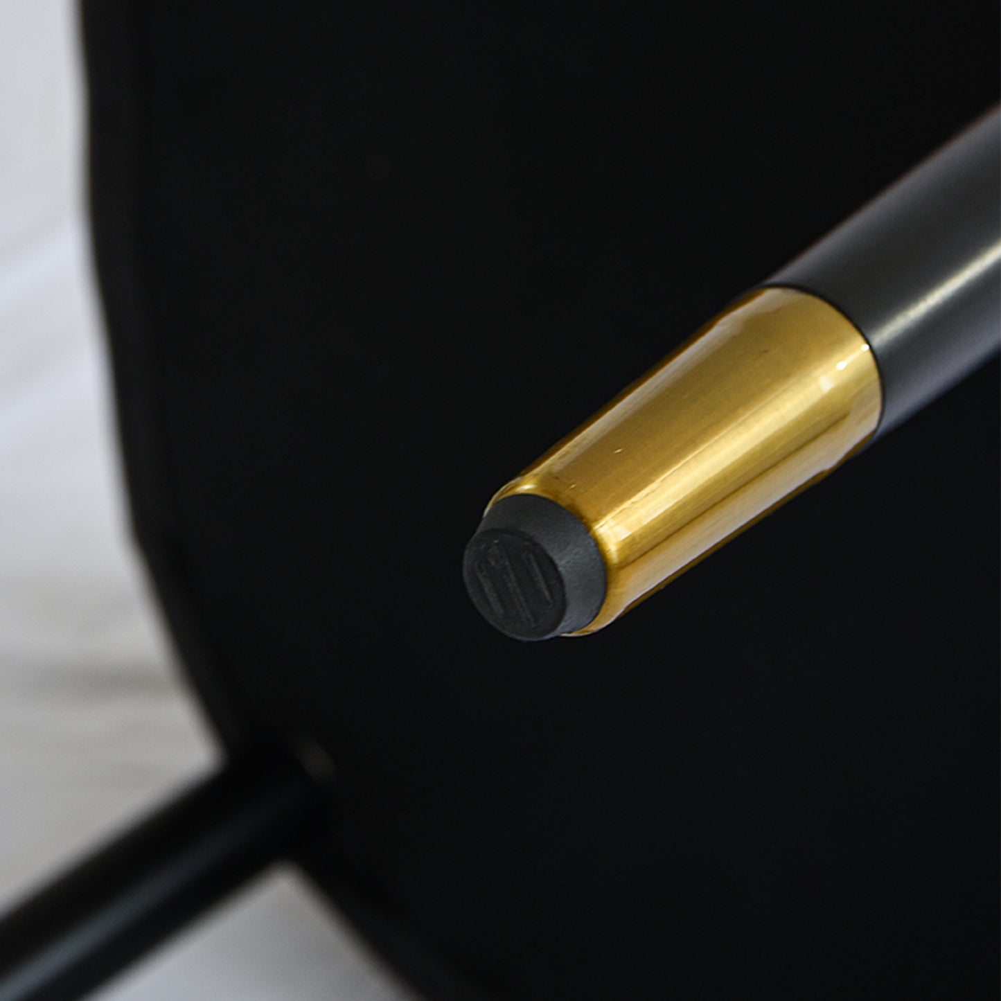 Close up of a black chair leg with a gold accent and rubber foot