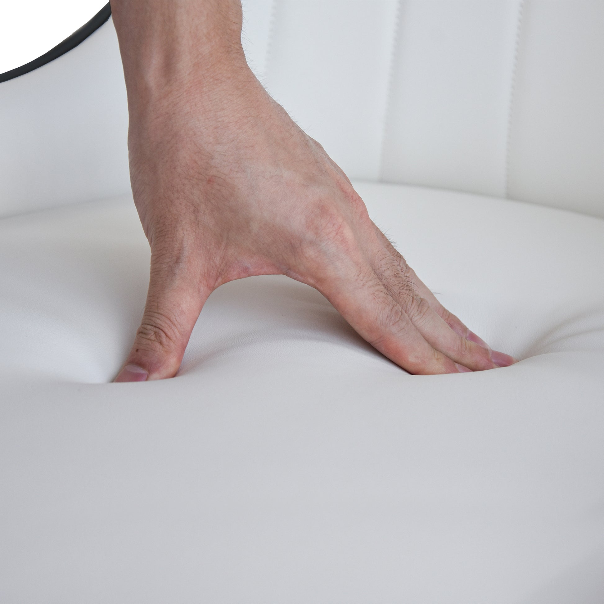 Hand pressing into white faux leather seat highlighting cushion comfort