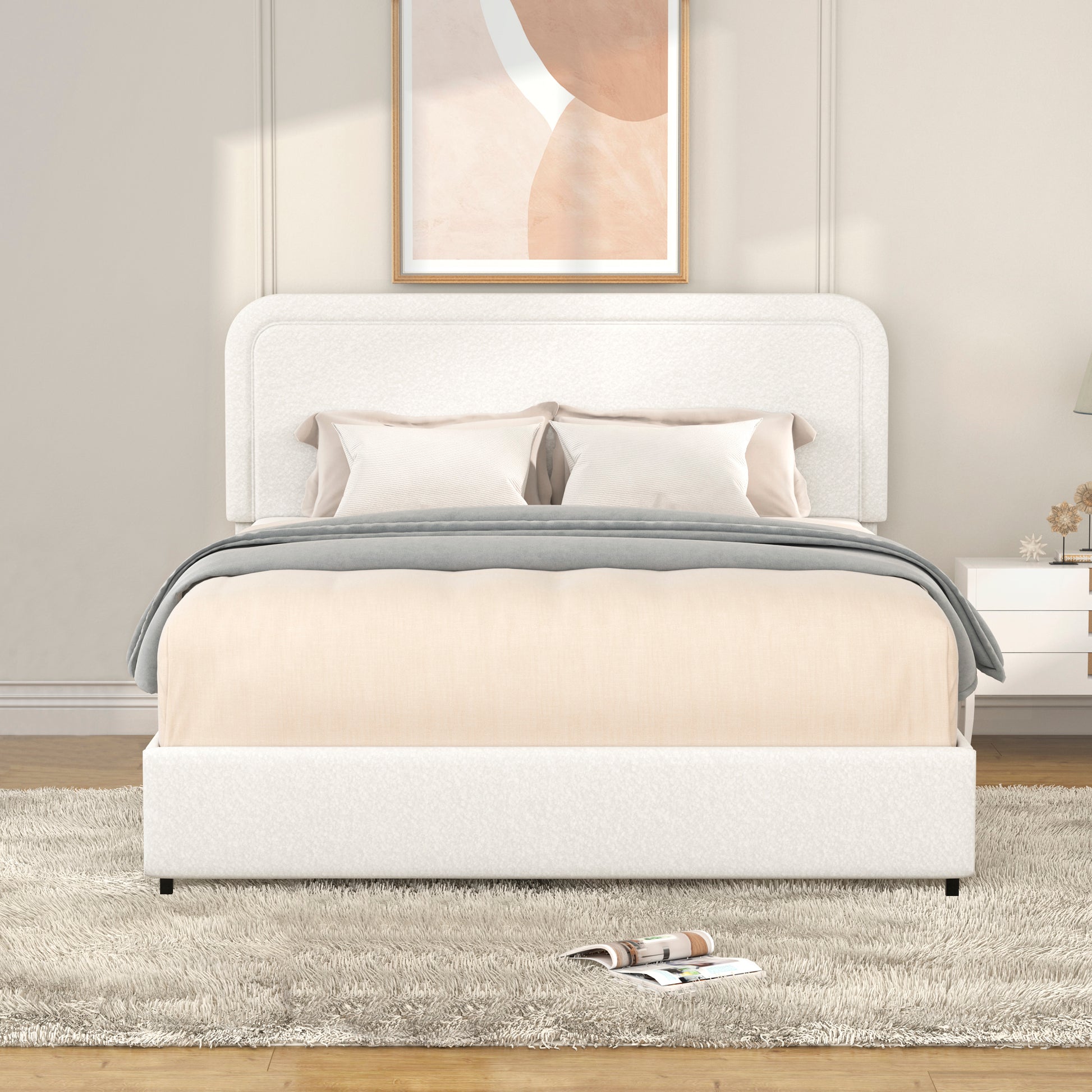 Upholstered white platform bed with rounded headboard and beige bedding featuring a plush rug
