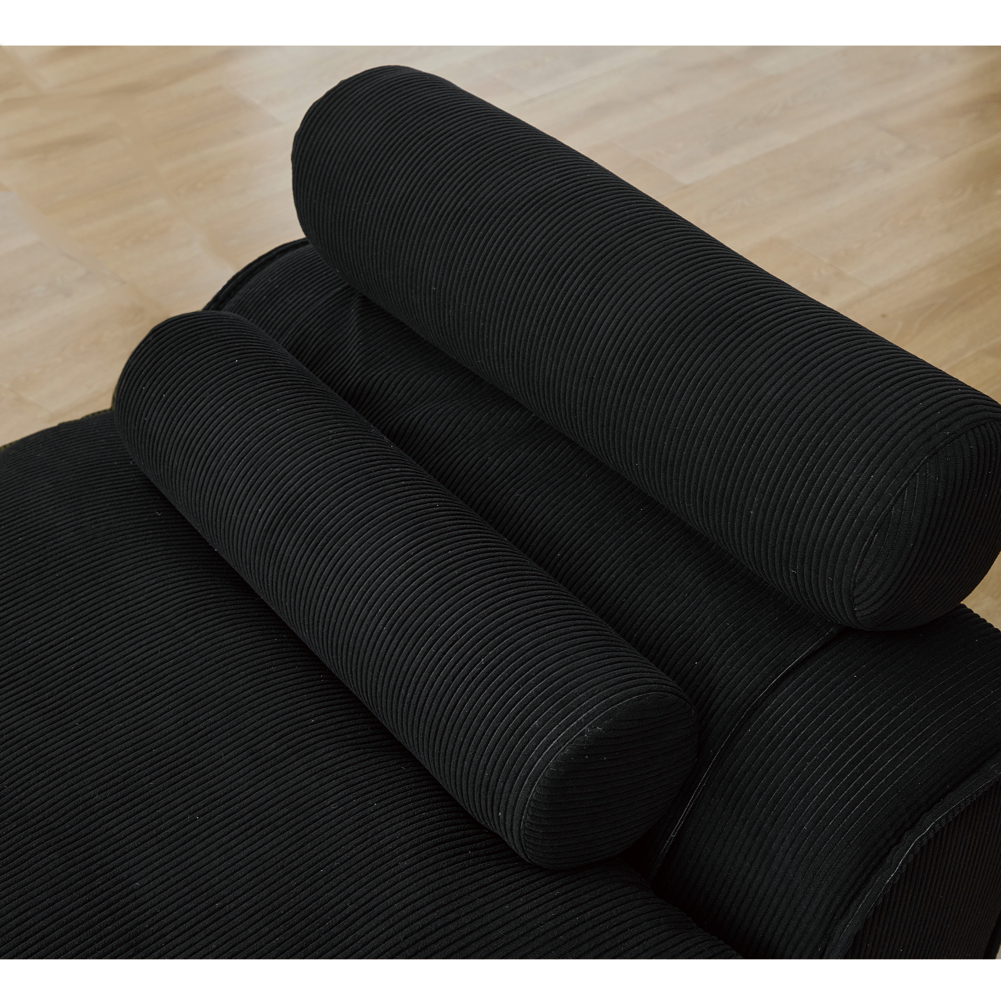 Closeup of a black corduroy bolster pillow on a modern sofa